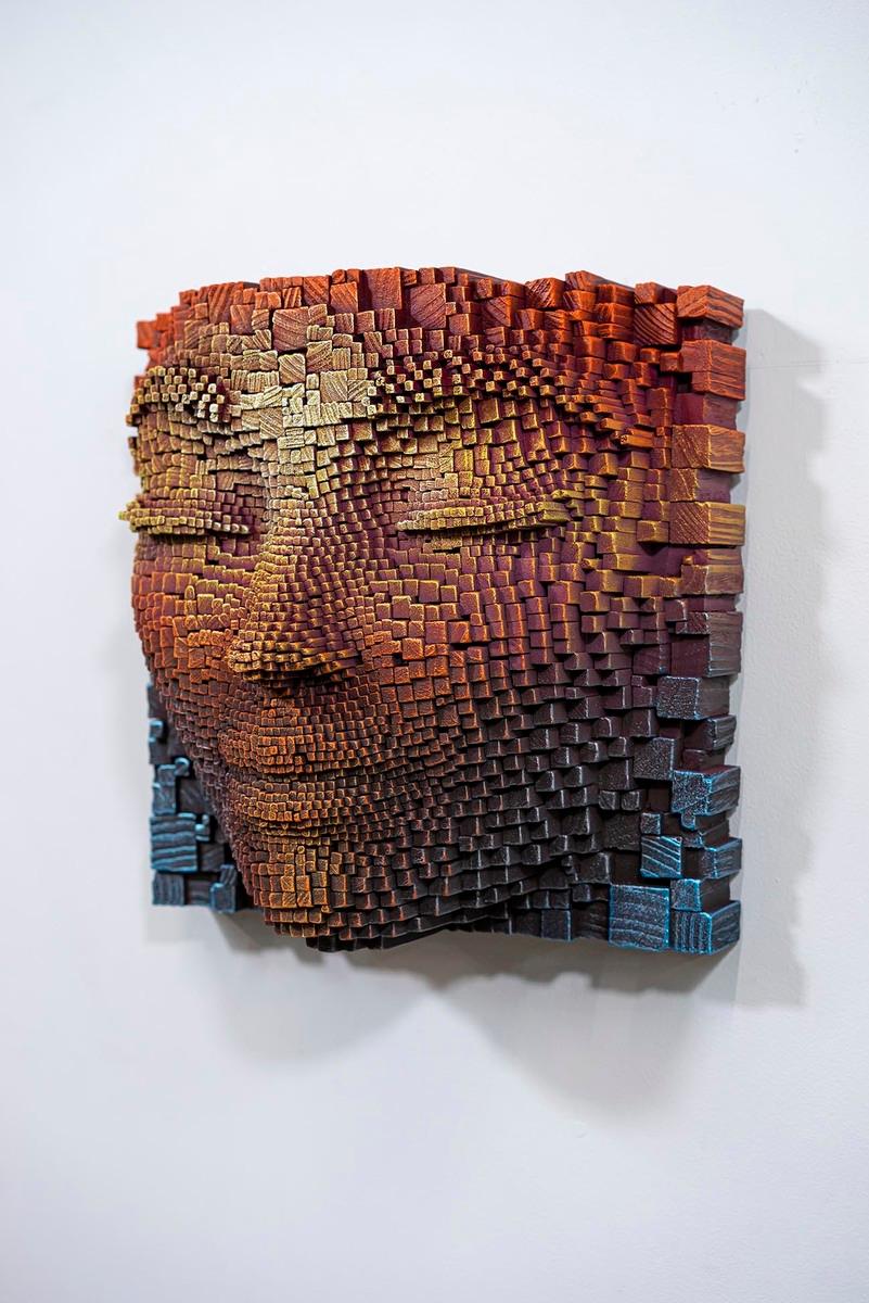 Questa affascinante opera è una scultura contemporanea che raffigura un volto umano, creata con pezzi di legno accuratamente assemblati. Ogni elemento, scolpito meticolosamente, varia di dimensione per modellare i contorni precisi e sereni del viso.