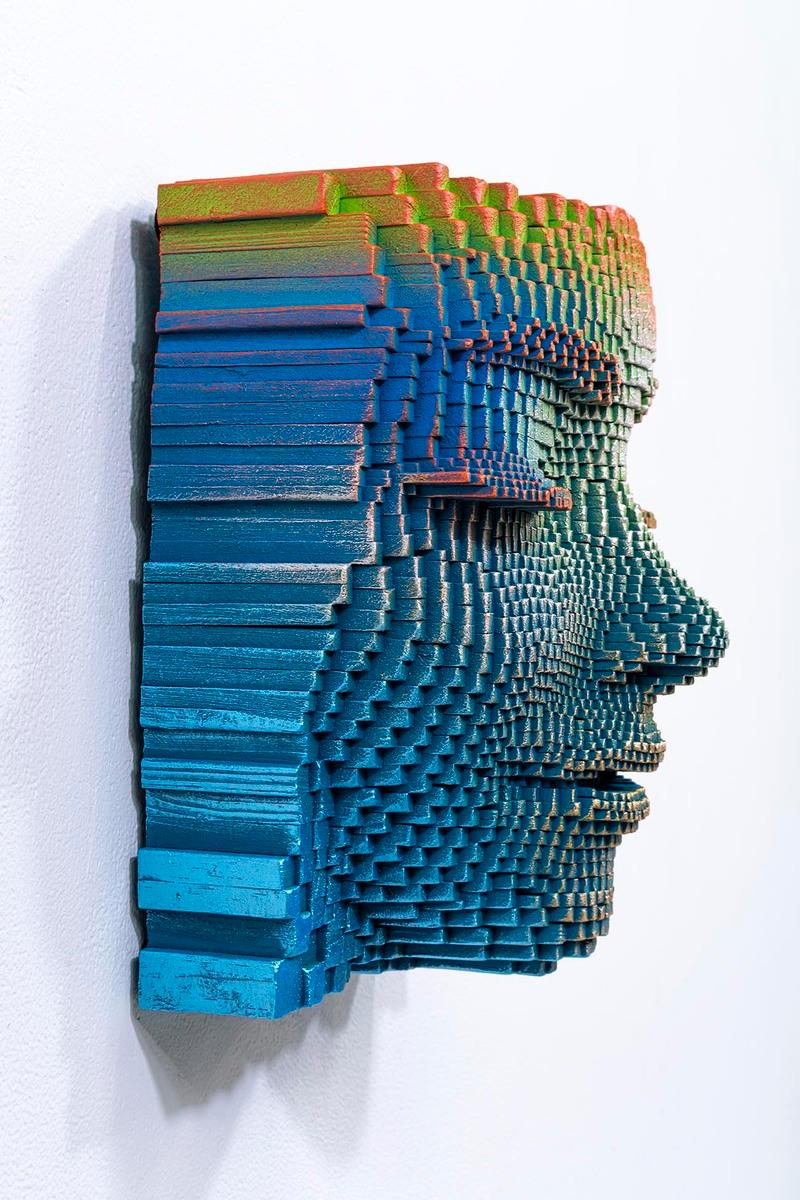 Cette œuvre d'art fascinante représente un visage serein, sculpté à partir d'un assemblage complexe de petites pièces de bois tridimensionnelles. Chaque élément méticuleusement sculpté contribue à la texture et à la profondeur uniques du visage. Les