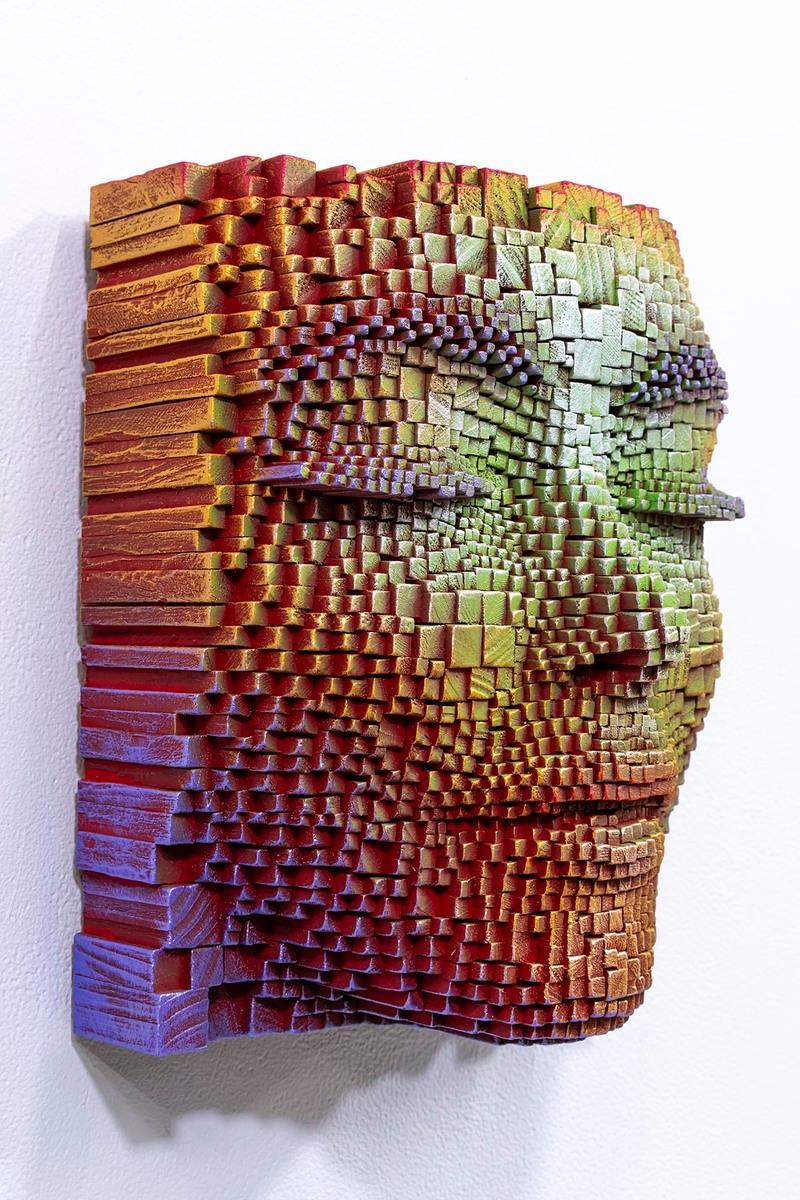 This captivating artwork features a serene face, sculpted from multiple wooden cubes, creating a fascinating three-dimensional illusion. The cubes, varying in size, come together to form a subtle relief, with each block contributing to the