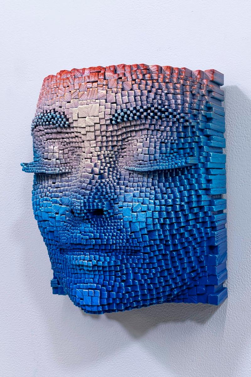 Esta sorprendente obra de arte presenta una escultura en relieve de un rostro humano, elaborada con notable precisión. El artista ha elegido cuidadosamente una paleta de azules y rojos que se mezclan armoniosamente, creando una profundidad y una