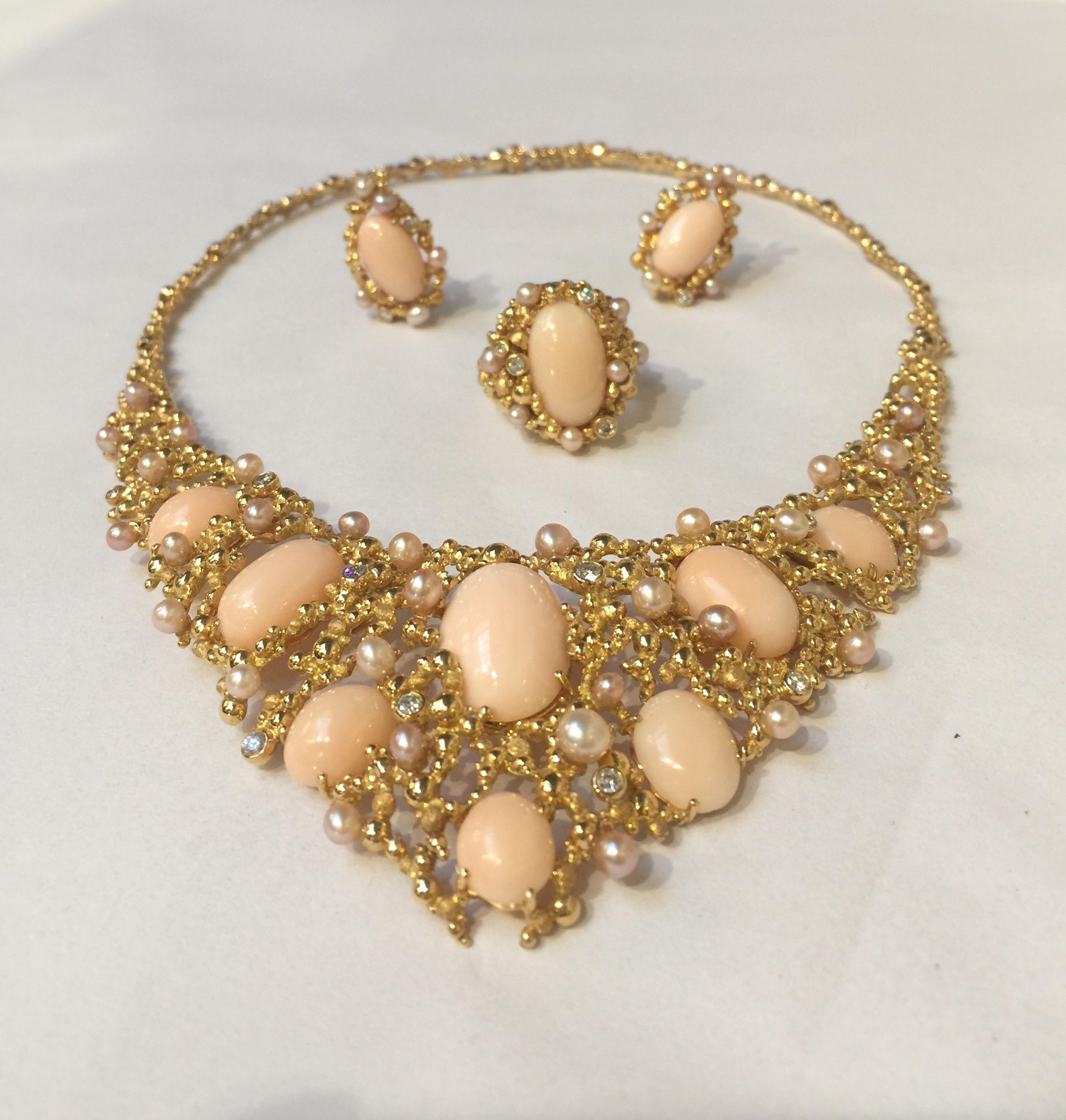 A fantastic jewelry suite by legendary Swiss jeweler Gilbert Albert, of pink angel skin coral, cultured pearls, and diamonds, all set in 18k yellow gold. The suite comprising of a large bib necklace with matching ring (size 7) and earclips. 

The