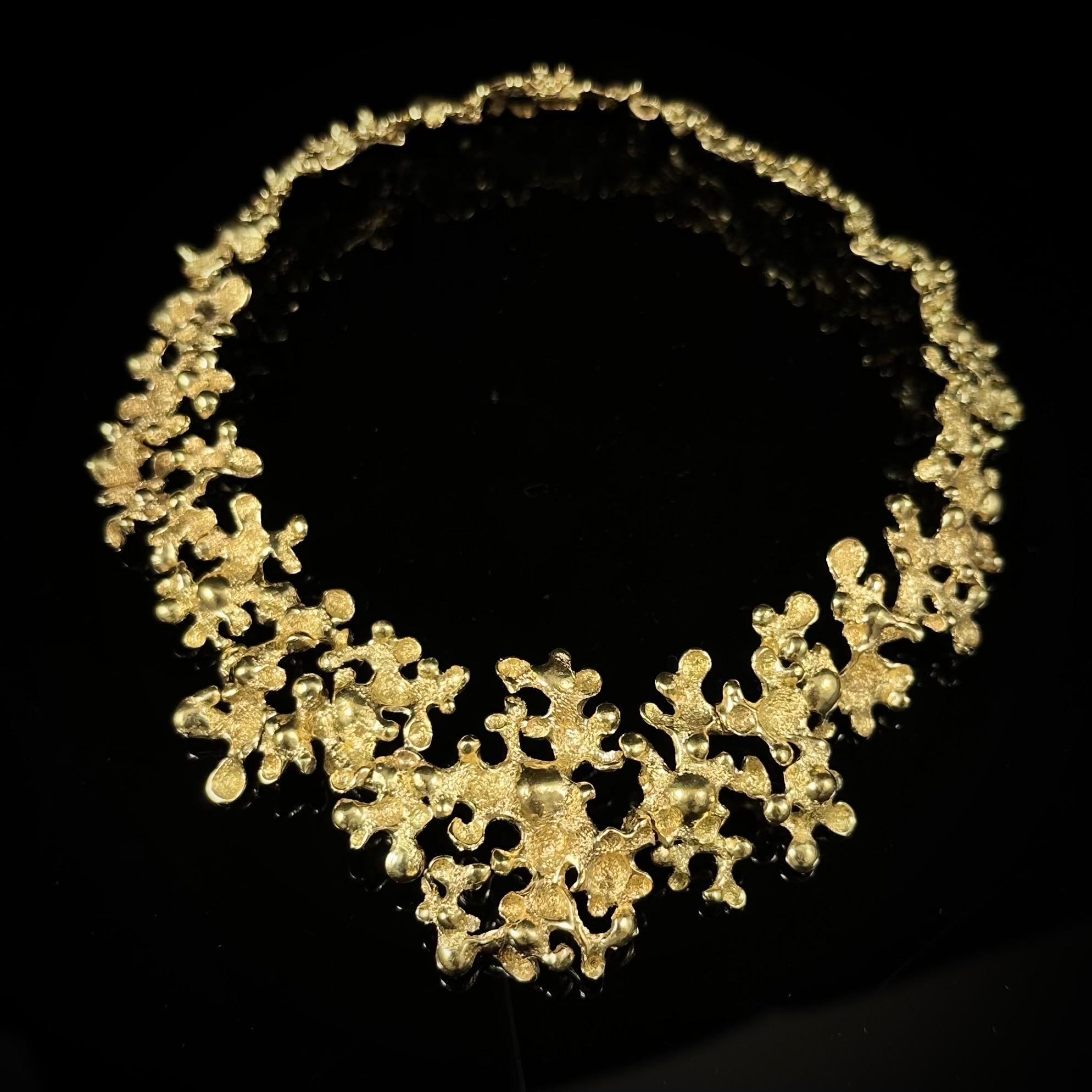 Gilbert Albert vintage floral bib necklace in 18kt yellow gold, Switzerland, 1970s. Modelled as a sequence of asymmetrical openwork floral botryoidal panels with both polished and granular textured decoration, graduating in size from larger sections