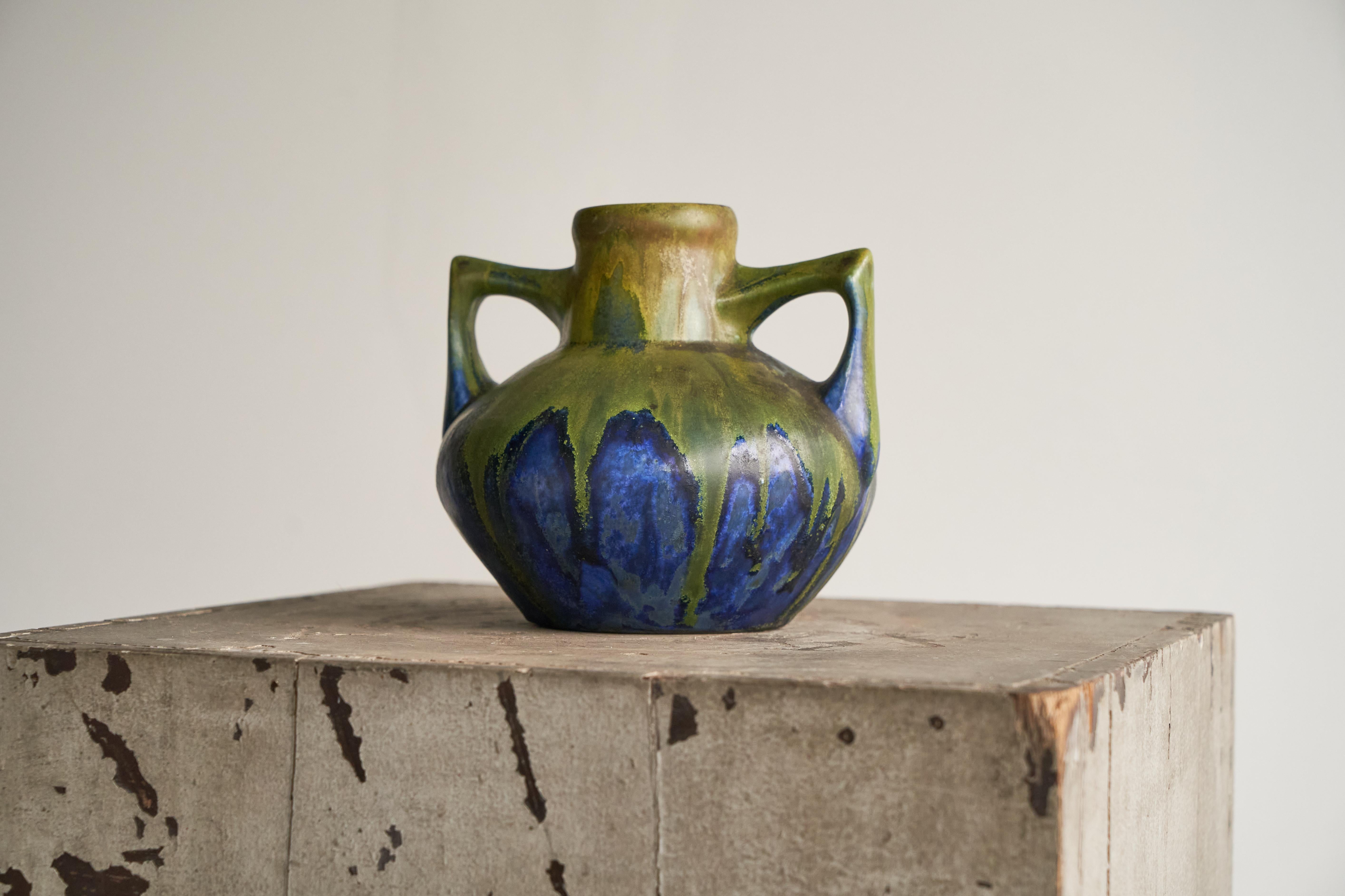 Ce magnifique vase Art déco est une pièce rare de l'artiste céramiste français Gilbert Méténier (France, 1844 - 1922).

Le vase est de bonne taille et présente deux poignées intéressantes qui se détachent doucement de la forme principale. Les