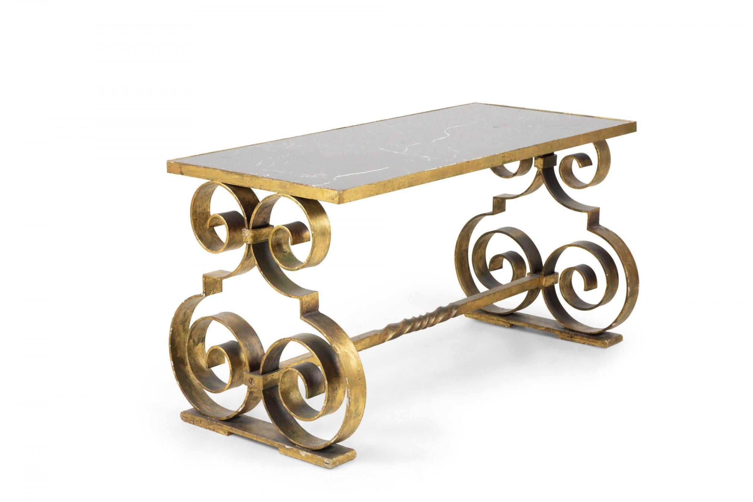 French Art Deco rectangular gilt iron coffee table with double scroll shaped sides and a stretcher base, supporting an inset black marble top. (style of GILBERT POILLERAT).
     