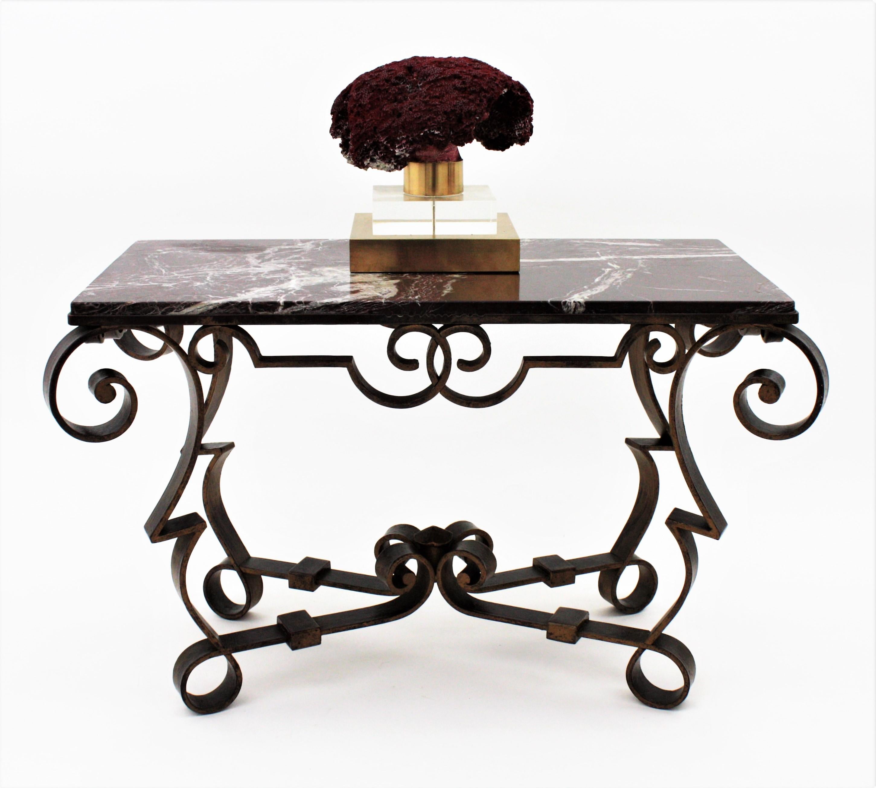 Gorgeous handwrought iron parcel-gilt cocktail / side table with red, black and white marble top. Attributed to Gilbert Poillerat, France, 1940s.
This low table has an elegant design with pure lines and accents of Baroque and Gothic styles. It is