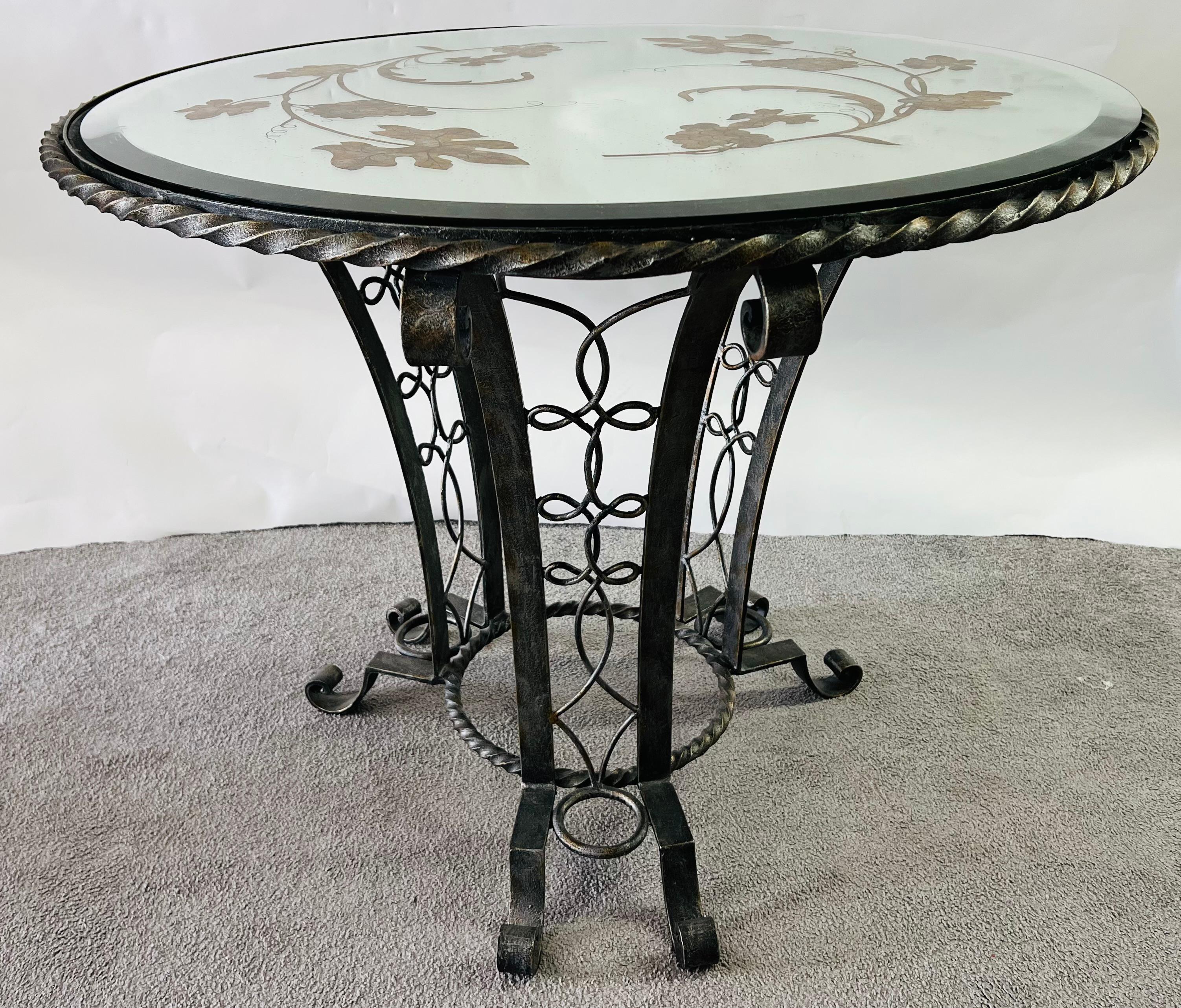 Art Deco wrought Iron center table in the style of Gilbert Poillerat ( French 1902-1988). The table base is finely crafted made of patinated and gilded wrought iron, showing spectacular design and craftsmanship. The distressed mirror top is beveled