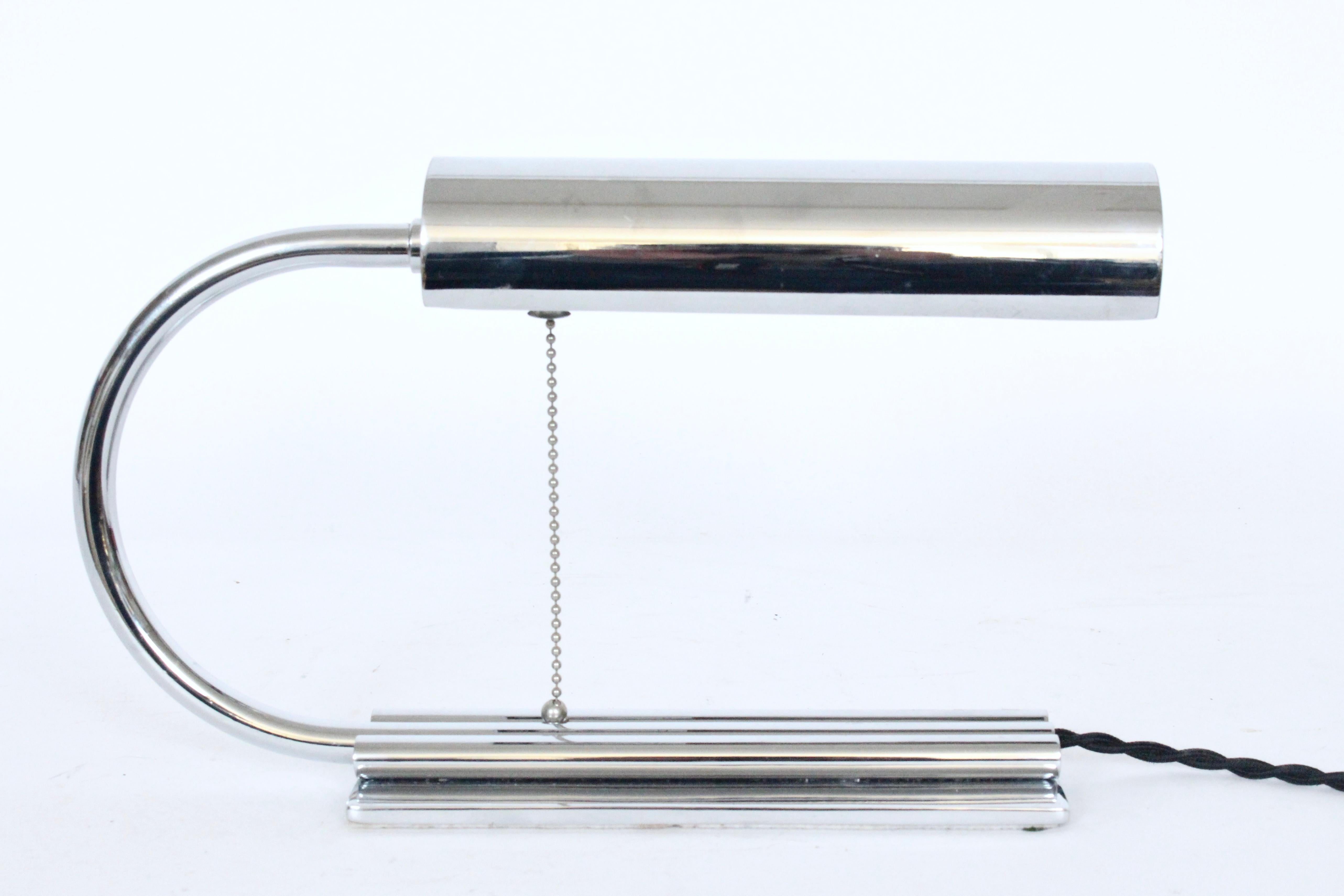 Streamline Moderne Gilbert Rohde style all chrome desk lamp. Featuring an arched Chrome plated Brass neck, rotating cylindrical head connecting to triple cylindrical tubes, center tube with cord chase, atop a footed rectangular base. With balled