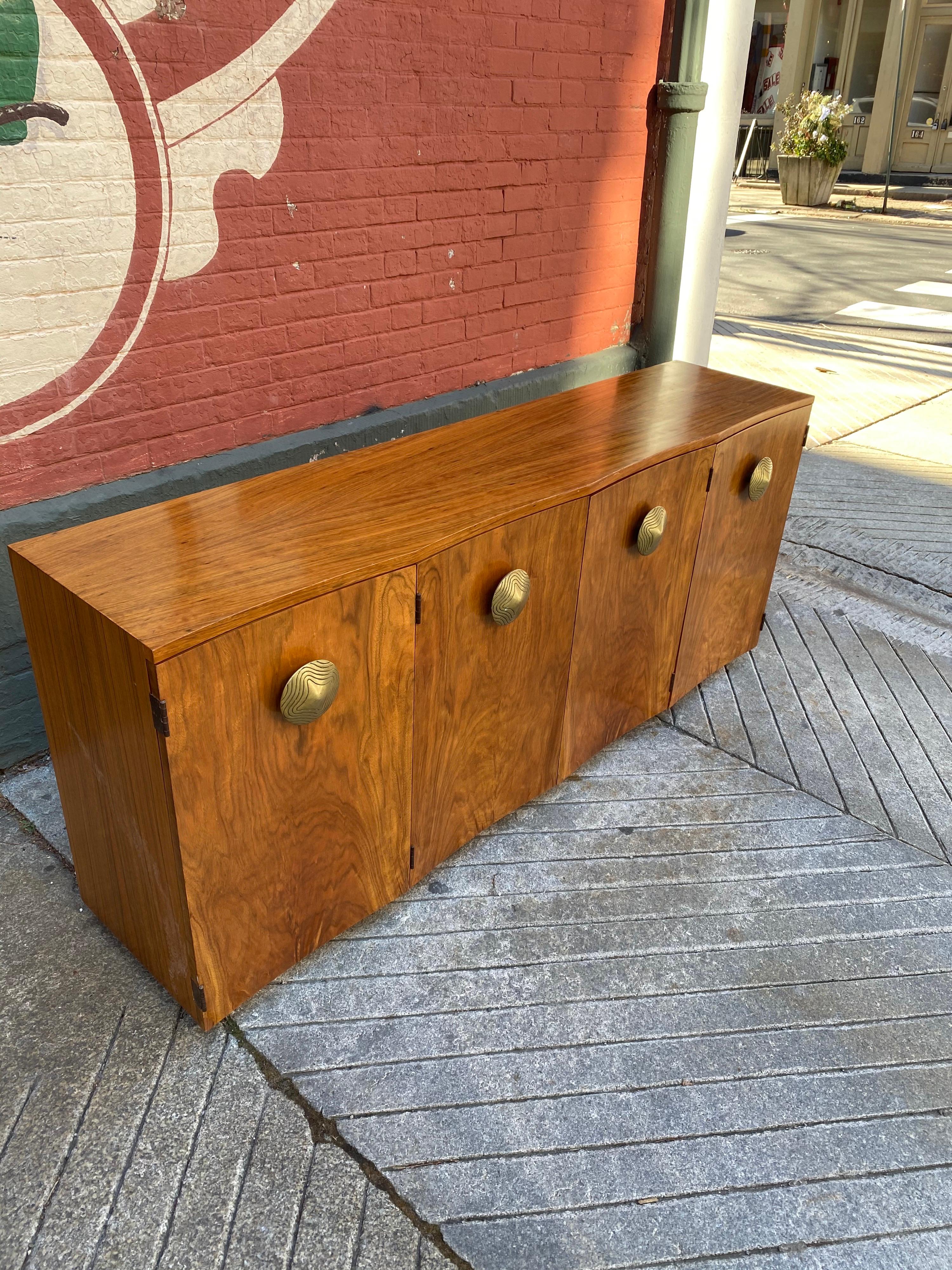 Gilbert Rohde Paldao curved front 4-door cabinet. One of the best designs from the Paldao line. Doors open to reveal ample storage with pull out drawers. Cabinet sits on a very short box base. Brass incised pulls add to this amazing cabinet!