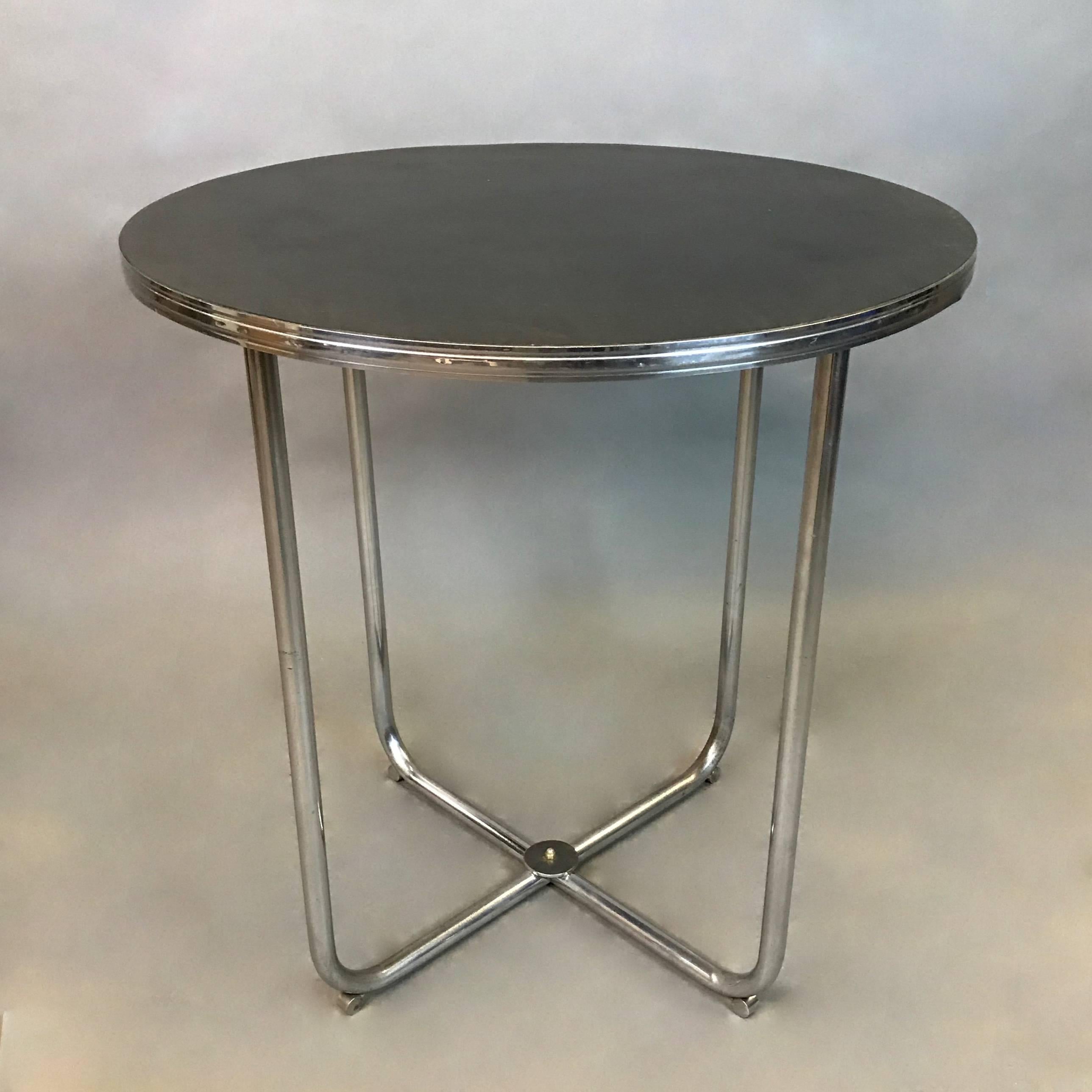 Art Deco, small dining or café table by Gilbert Rohde features a tubular chrome base with black laminate top trimmed in chrome.