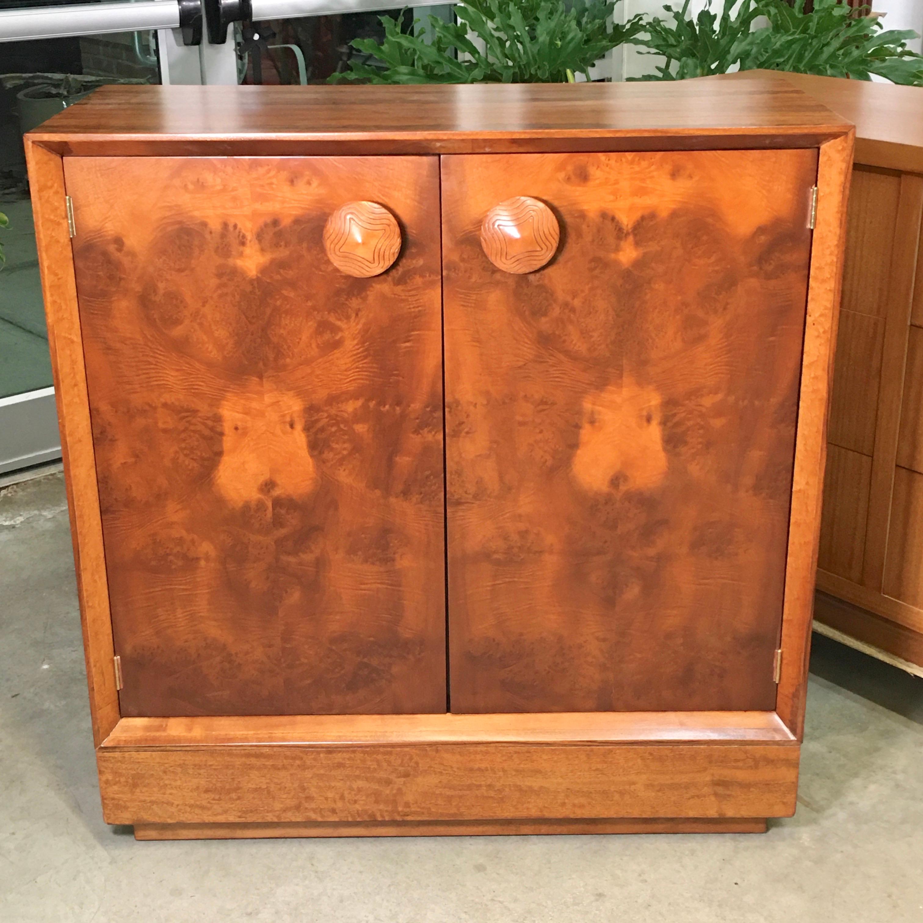 Gilbert Rohde designed this chest for Herman Miller as part of his 1941 Paldao Line of streamline modernist and modular furniture in exotic veneer. This is model no. 4103, two-door cabinet with distinctively incised large round pulls, interior