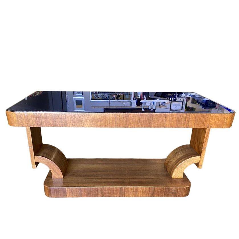 Table basse en acajou de style Streamline Art Déco de Gilbert Rohde avec un plateau en verre cobalt et une base en sablier moderniste. Le plateau de table, en verre bleu cobalt vibrant, crée un contraste saisissant avec les tons riches de la base en