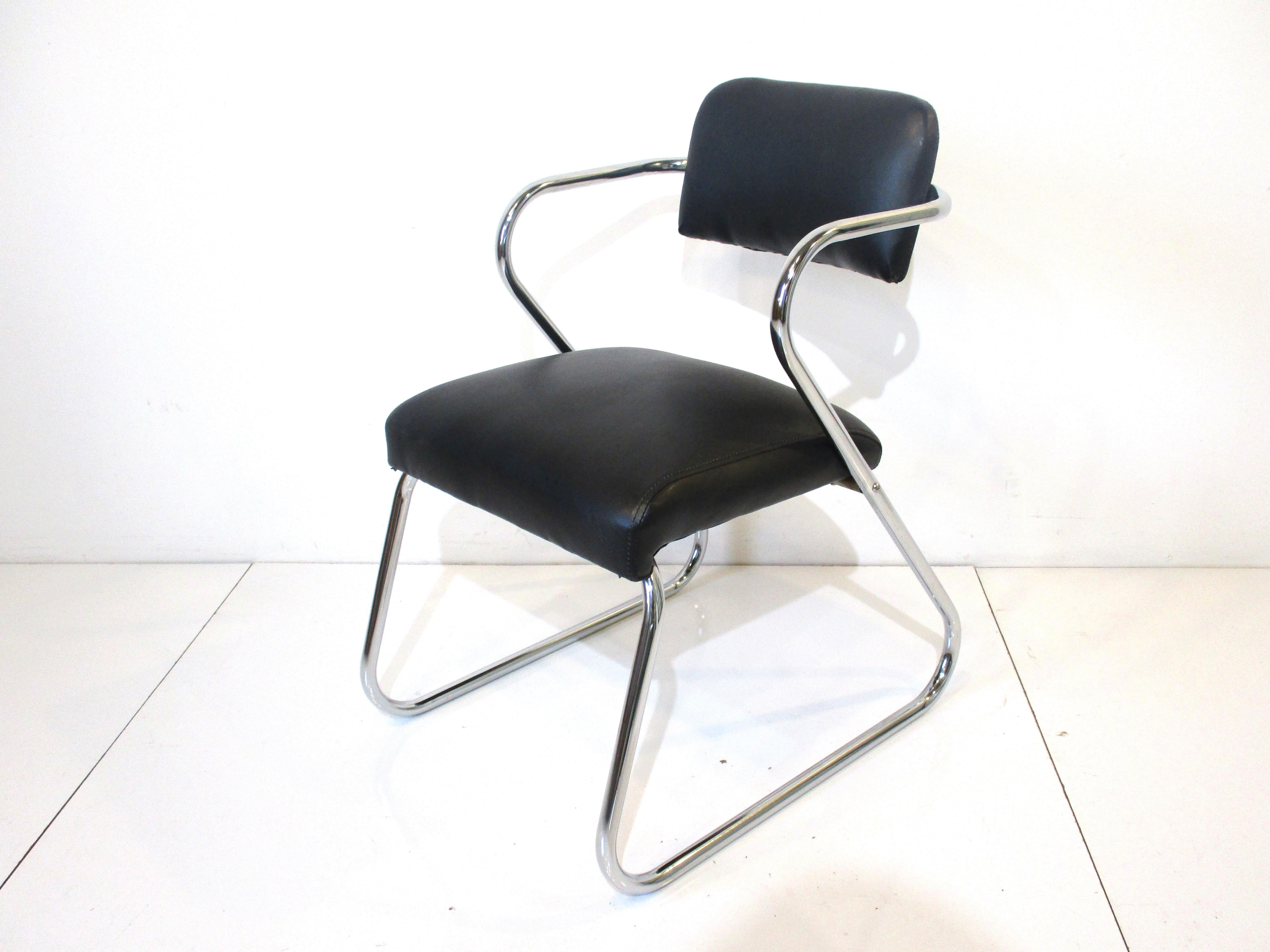 A set of four sculptural chromed framed dining chairs in the design manner of Gilbert Rohde's Z chairs . Upholstered in a satin black soft and smooth leatherette fabric which makes them very comfortable for long periods of sitting . Manufactured by