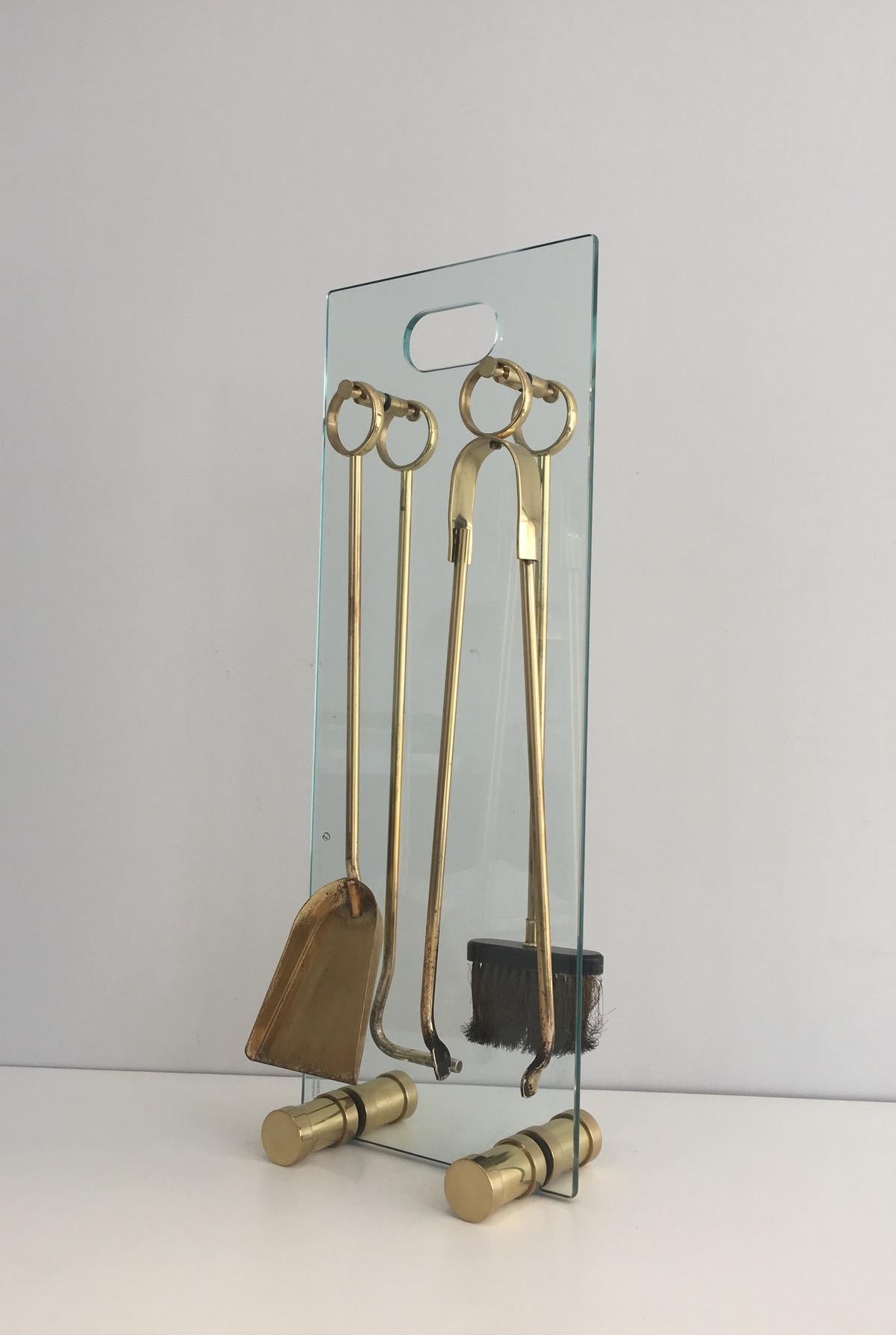This nice fire place tools are made of brass and are displayed on a tempered glass and brass base, French, circa 1970.