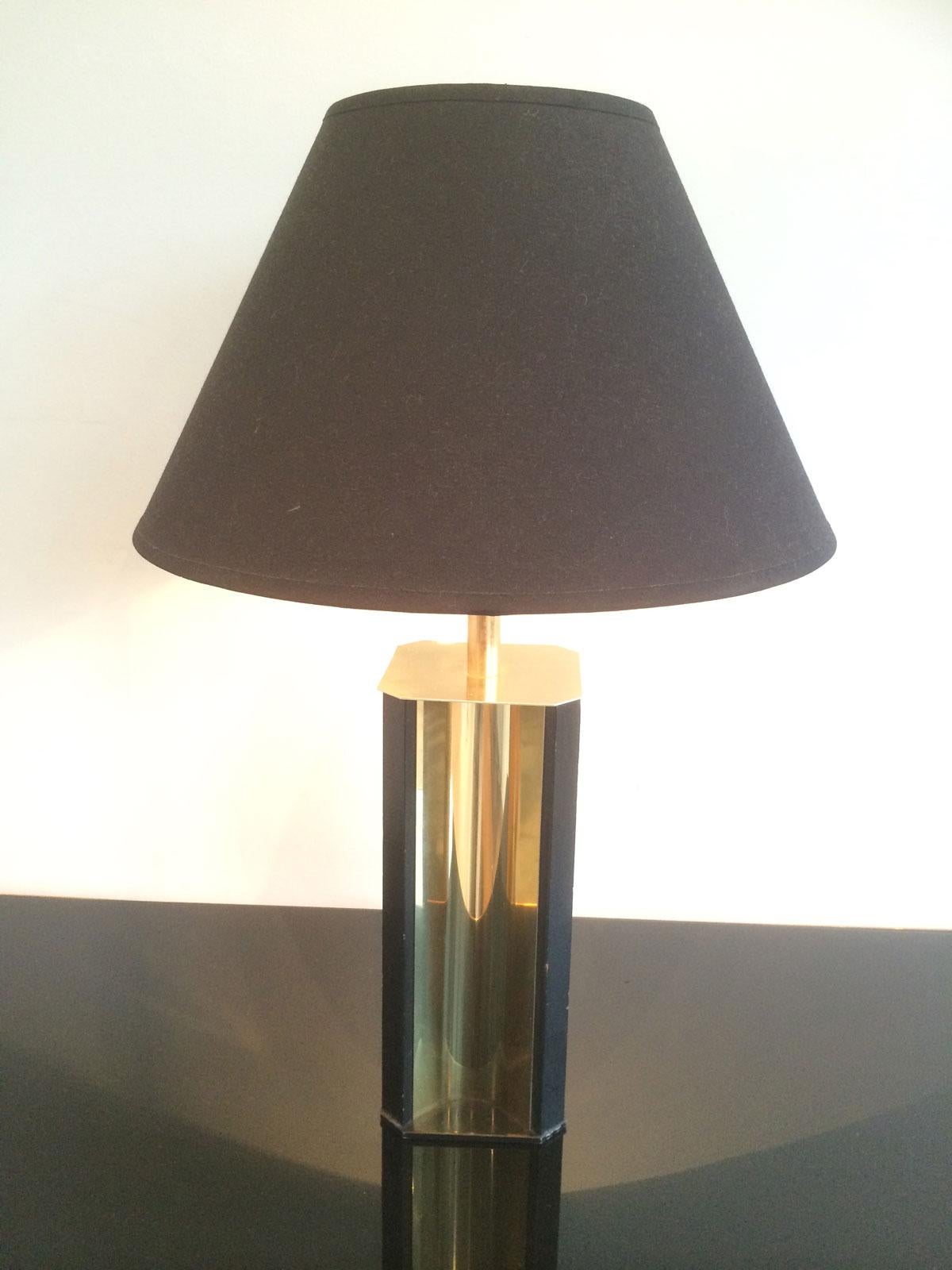 This table lamp is made of gilt metal and black lacquered wood. It has a convex gild metal base and a new black shintz shade gilded inside. This is a French work, circa 1970.
