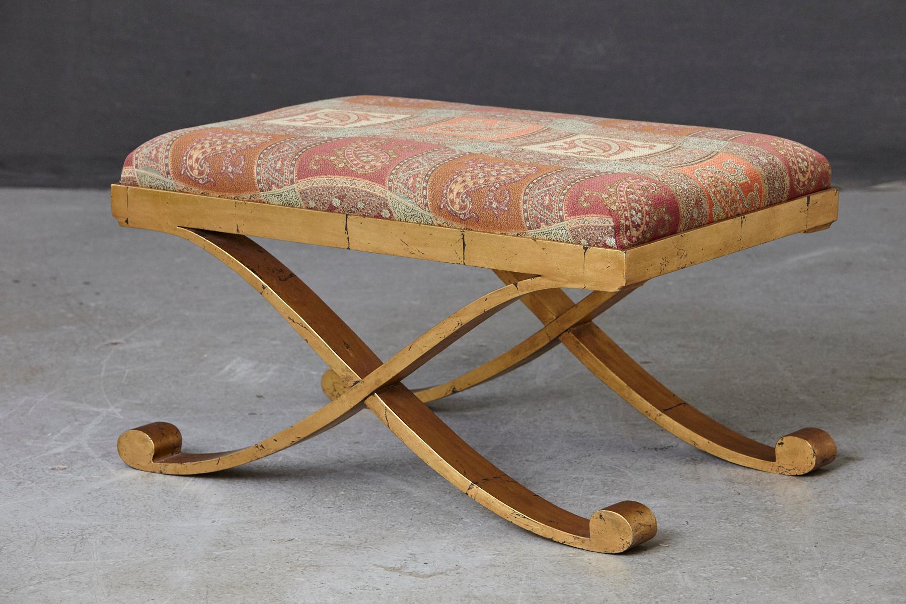 Lovely gild patinated metal bench with cross legs upholstered in Paisley fabric. Solid and sturdy metal construction, nice patina to the gild.