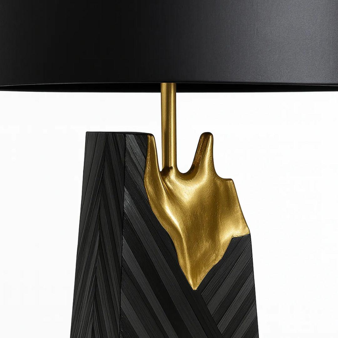 The Gild Straw Table Lamp by KOKET fuses bold design and fine craftsmanship, with black and gray straw marquetry split by a striking burst of hand-applied gold leaf. Finished with a sleek black shade, it radiates modern glamour.