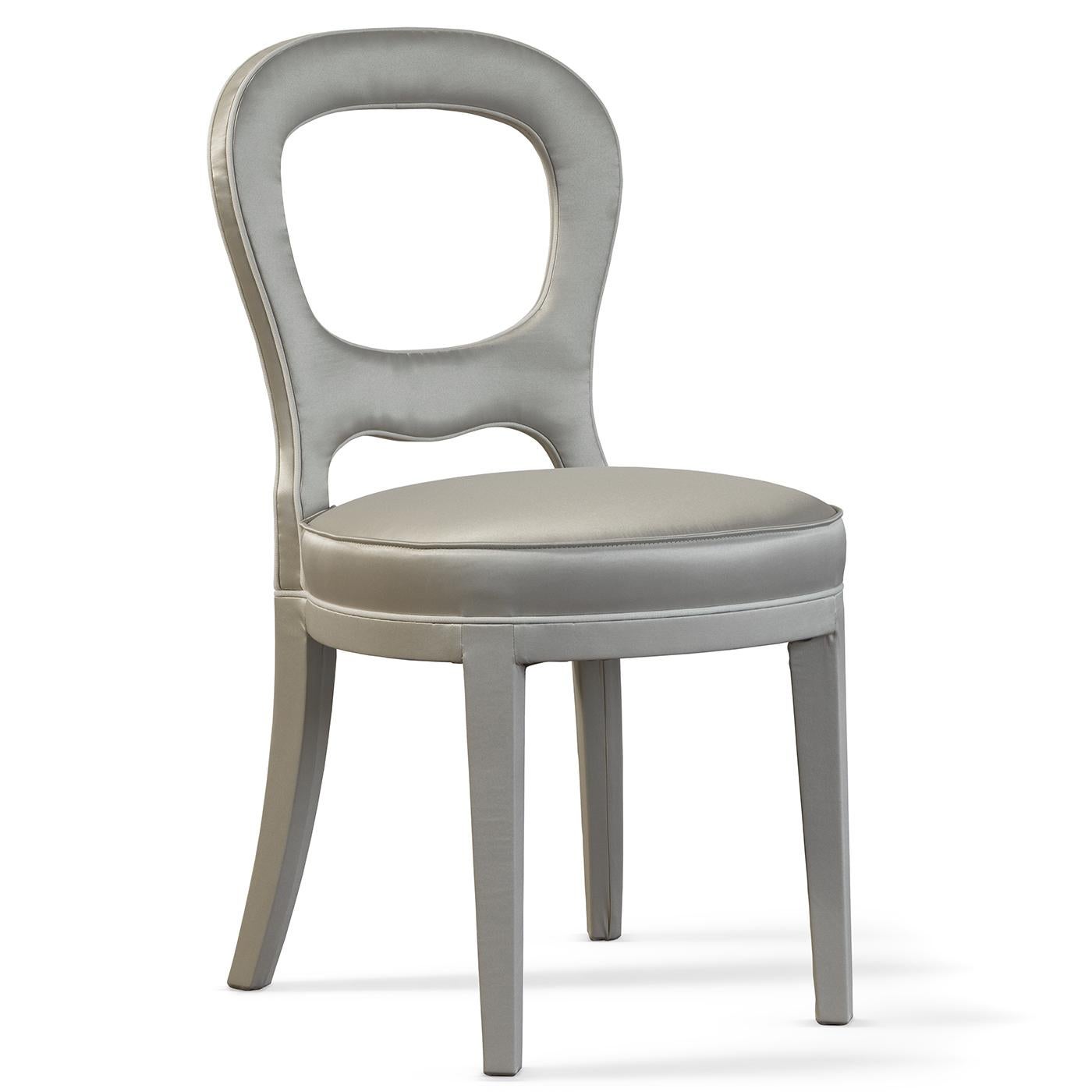 This elegant chair is part of the Gilda collection. Its solid beechwood structure is timeless and sophisticated and boasts a cut-out backseat. The entire shape of the piece is covered in a non-removable white fabric that lends it a subtle and