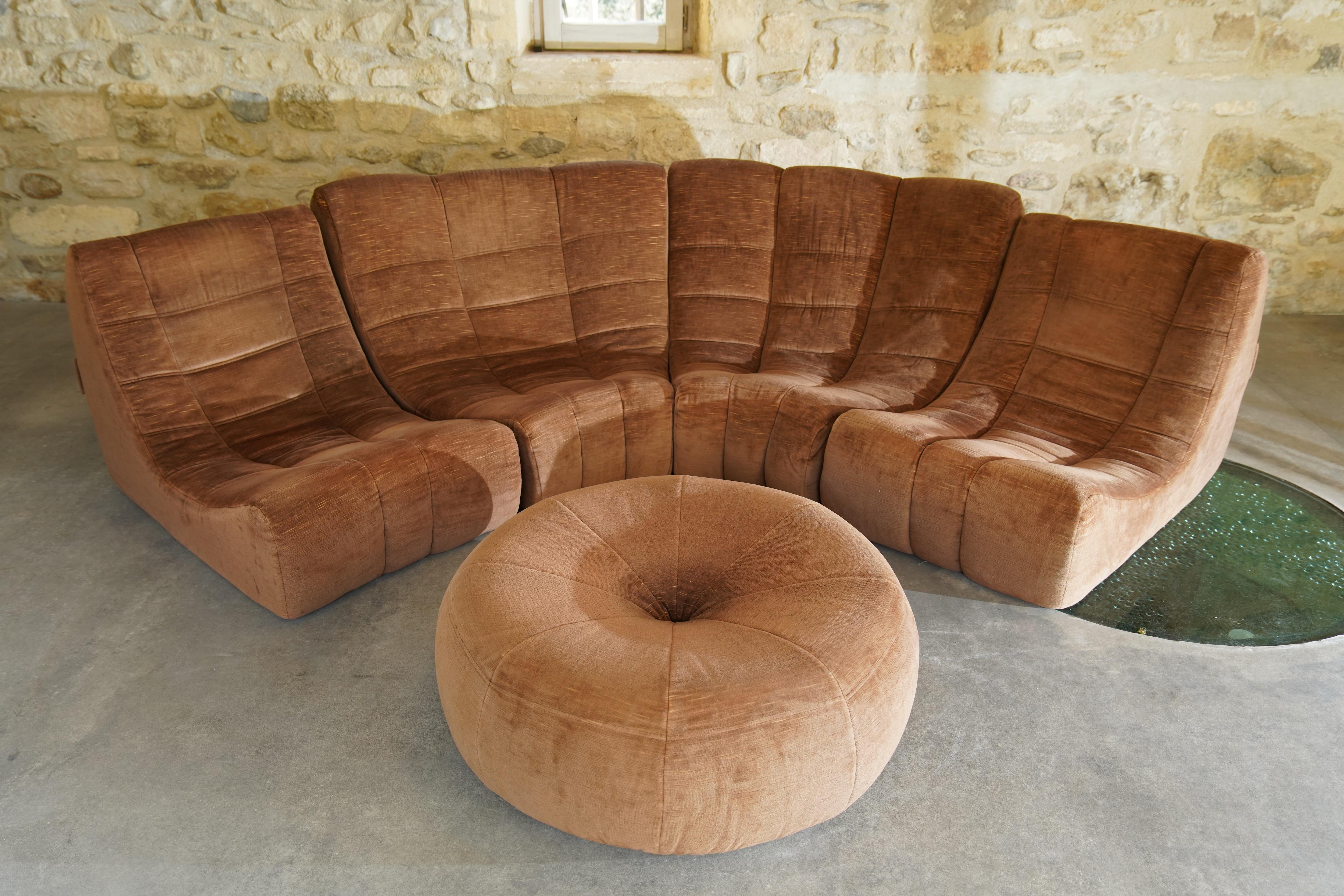 Rare canapé et ottoman 'Gilda' conçu par Michel Ducaroy pour Ligne Roset en velours brun. L'ensemble comprend 4 chaises reliées entre elles et un ottoman, rarement vu, en tissu assorti.

Le canapé Gilda, composé de confortables modules incurvés, est
