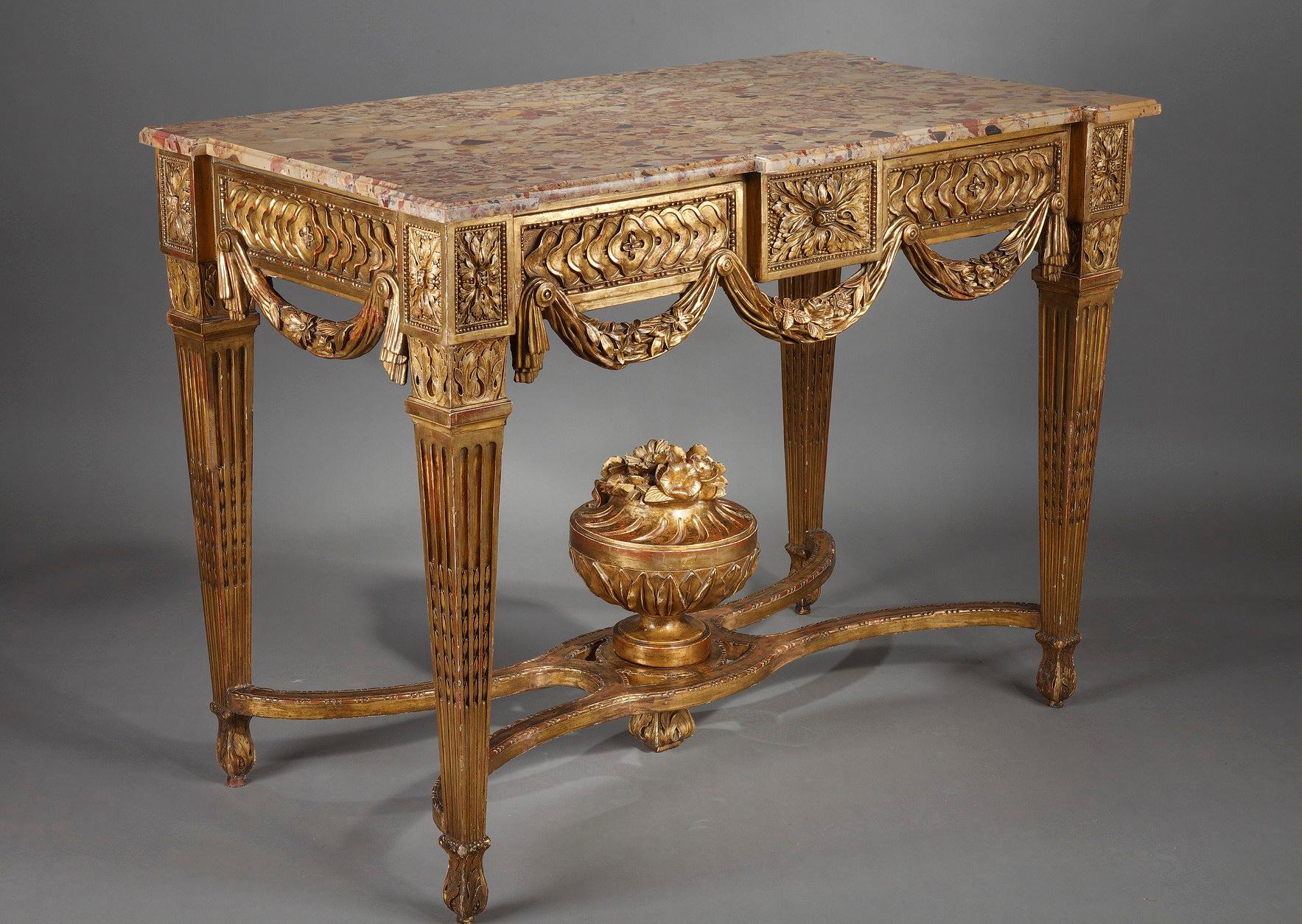Beautiful console in the Louis XVI style in gilded and carved wood topped by a brocatelle marble top, resting on four fluted and filleted pilaster feet, joined by an X-shaped brace supporting a flowering vase in its center. The belt is decorated