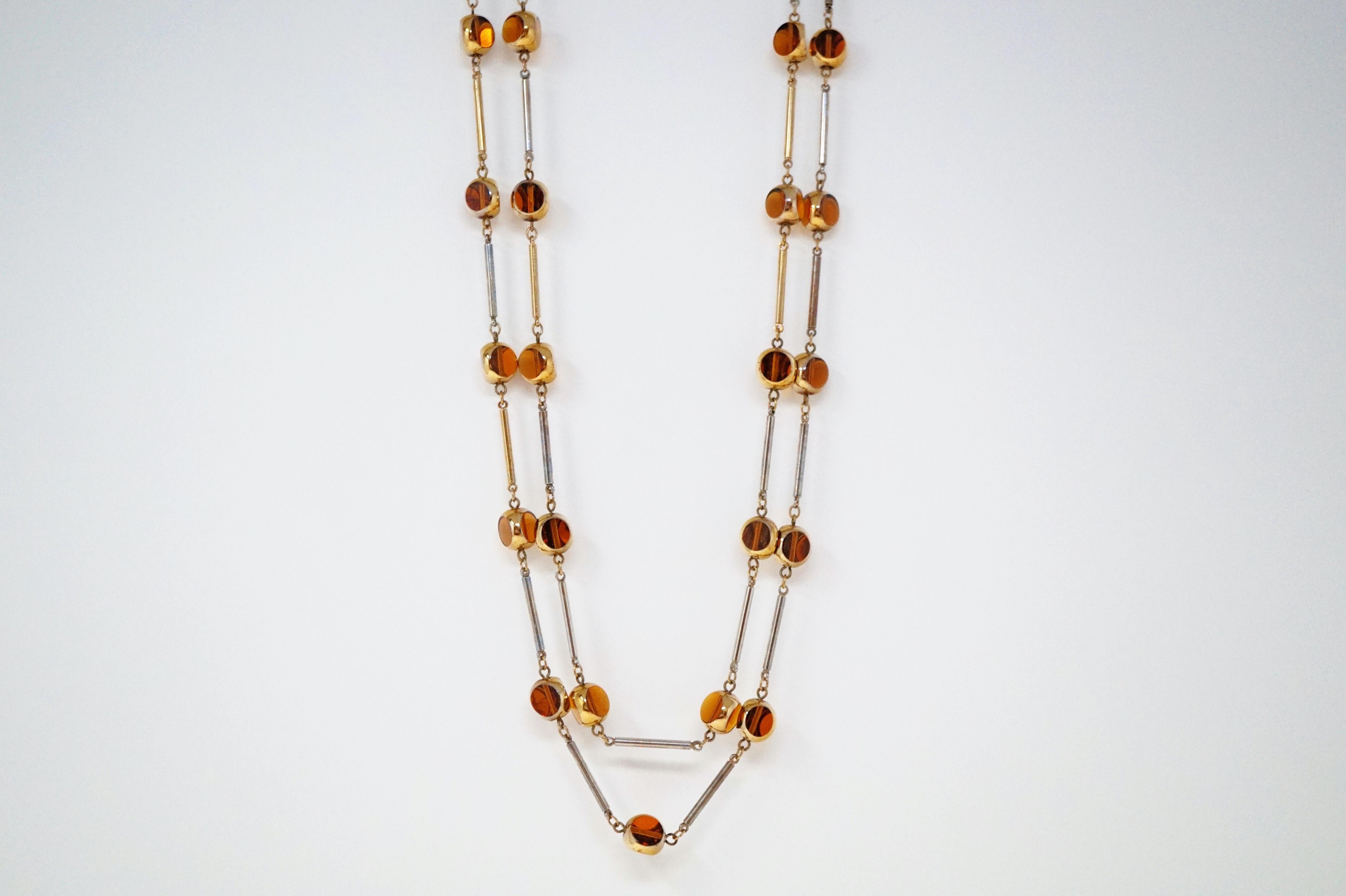 This groovy necklace and earrings set by Bergère is the epitome of 70s chic!  A double stranded necklace comprised of smokey brown glass cubes with gold-plated rounded edges linked with gilded bars make for a unique twist on the classic station