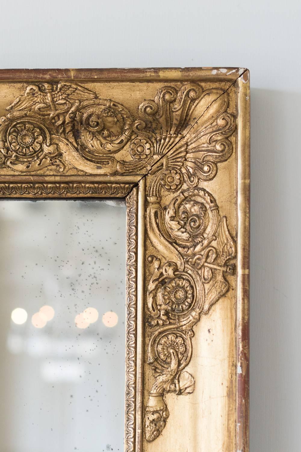 Gorgeous, wide- framed antique mirror with large medallion themed flowers. Rams, fireflies and more emanate from the frame. The design details are quite unique and add beautiful depth to this piece. Some distressing on the original glass. Stunning