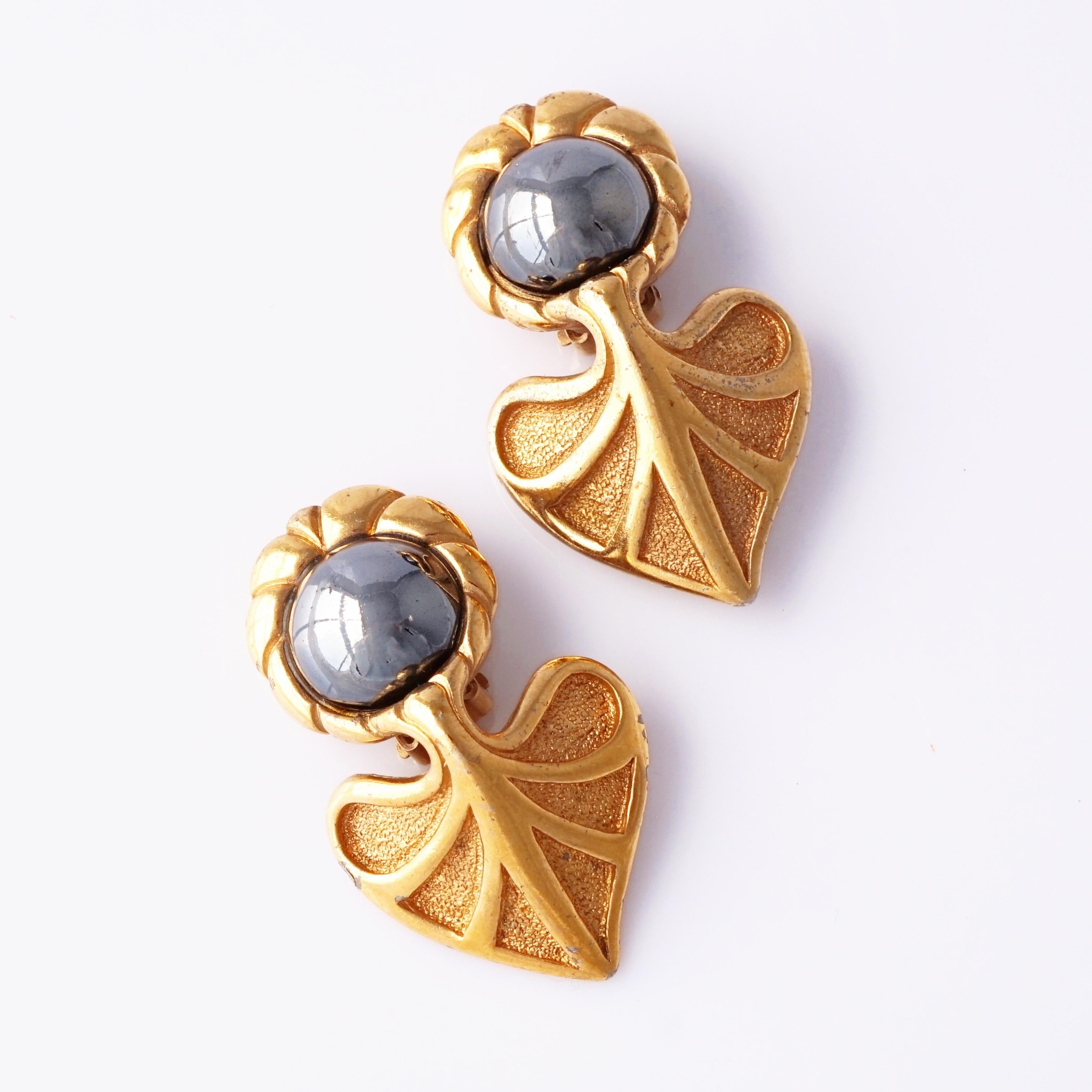 Questi orecchini di Guy Laroche, risalenti agli anni '80, incarnano l'inconfondibile miscela di raffinatezza parigina e forme moderne e audaci. Ogni orecchino presenta un cabochon di ematite lucida incorniciato da un motivo a foglia stilizzato in
