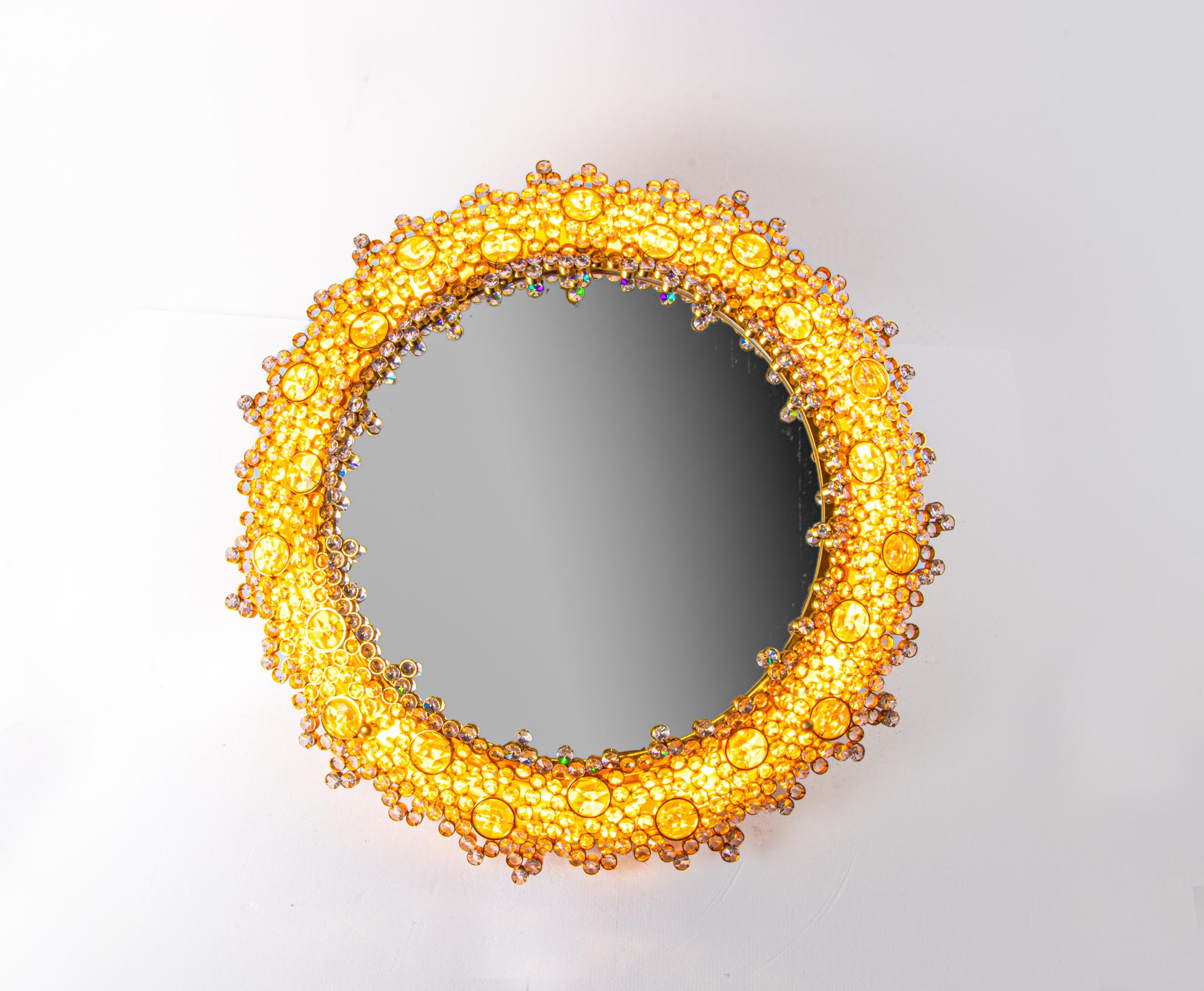 Élégant miroir rétroéclairé rond avec des cristaux autrichiens Swarovski facettés sur un cadre en laiton doré. Conçu par Christoph Palme. Dispose de 10 prises. En très bon état. Il s'agit de l'un de ces designs fantastiques qui s'adaptent à toutes