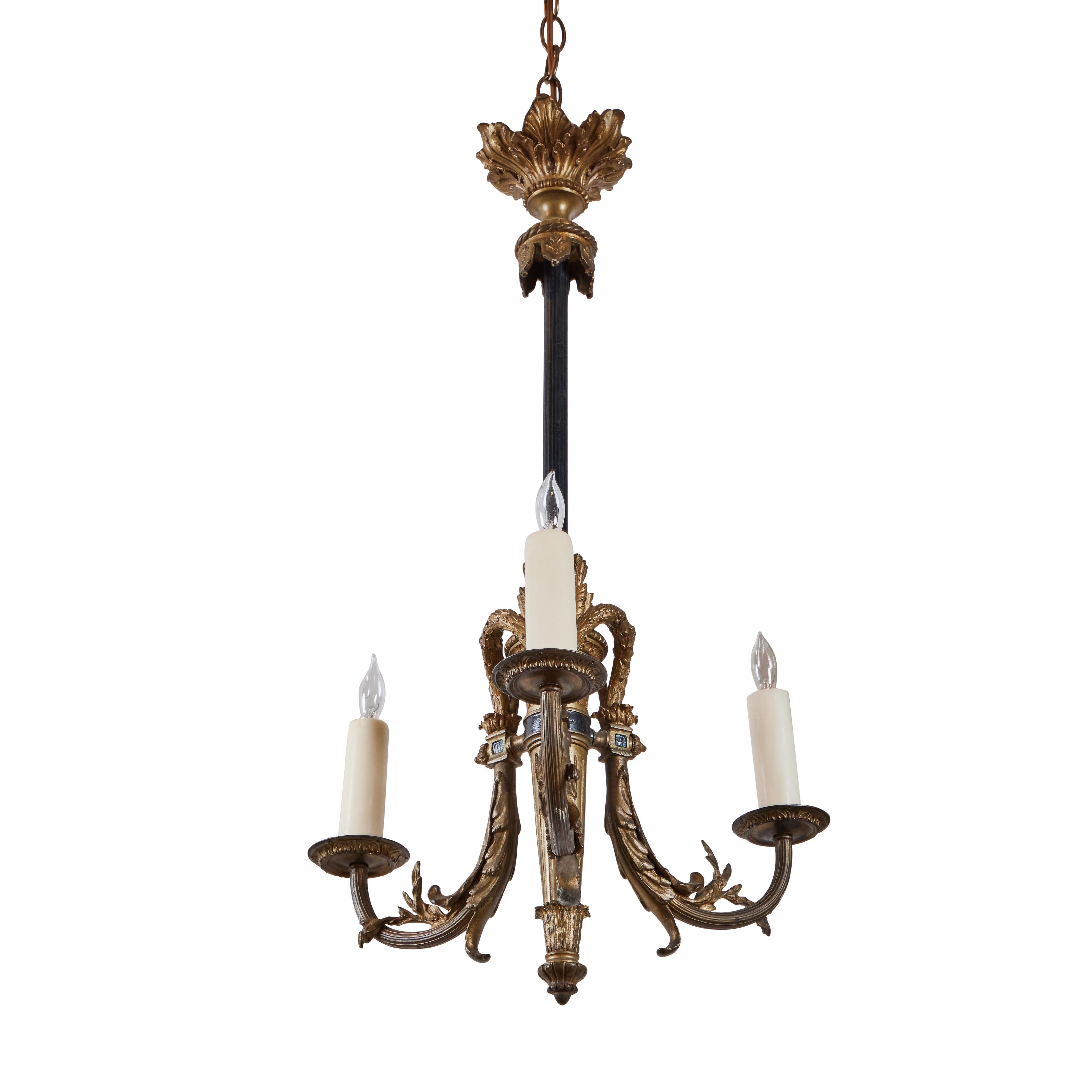 Gilded bronze and iron, three arm chandelier featuring a foliate canopy, torch-form central body and cascading leaf details. 3 lights. Wired for U.S.