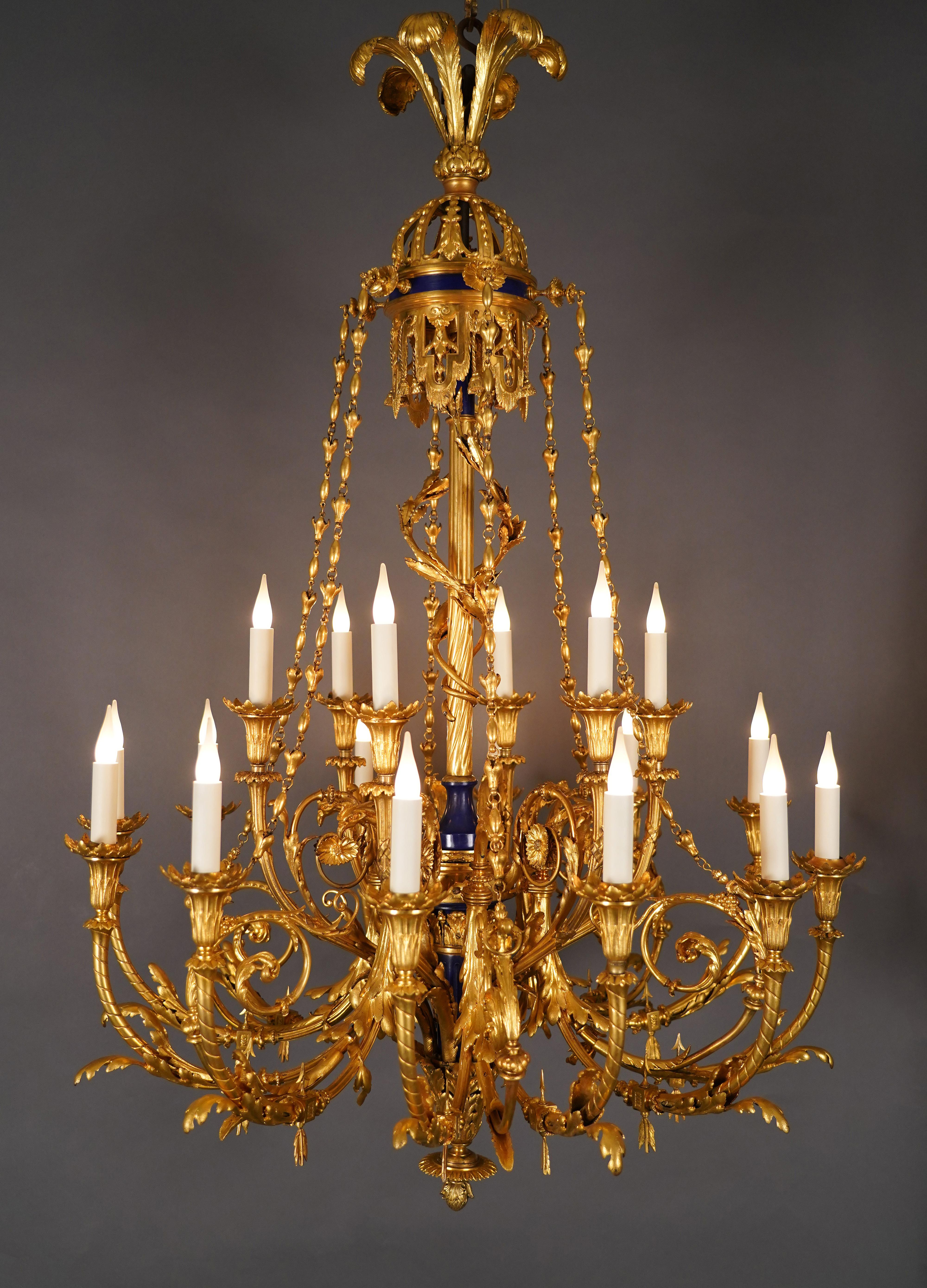 Important Louis XVI-inspired chandelier in gilded bronze with 18 lights. The central shaft is made up of a baluster-shaped dark blue cold-painted vase, surmounted by a fluted rod in gilded bronze surrounded by intertwined laurel branches, topped