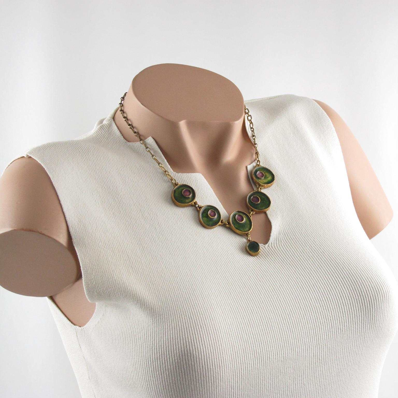 Questa deliziosa collana a girocollo in bronzo modernista francese presenta cinque elementi geometrici penzolanti in forme libere e arrotondate, sormontati da smalto verde e viola. Il pezzo vanta una bella catena in metallo dorato con chiusura a