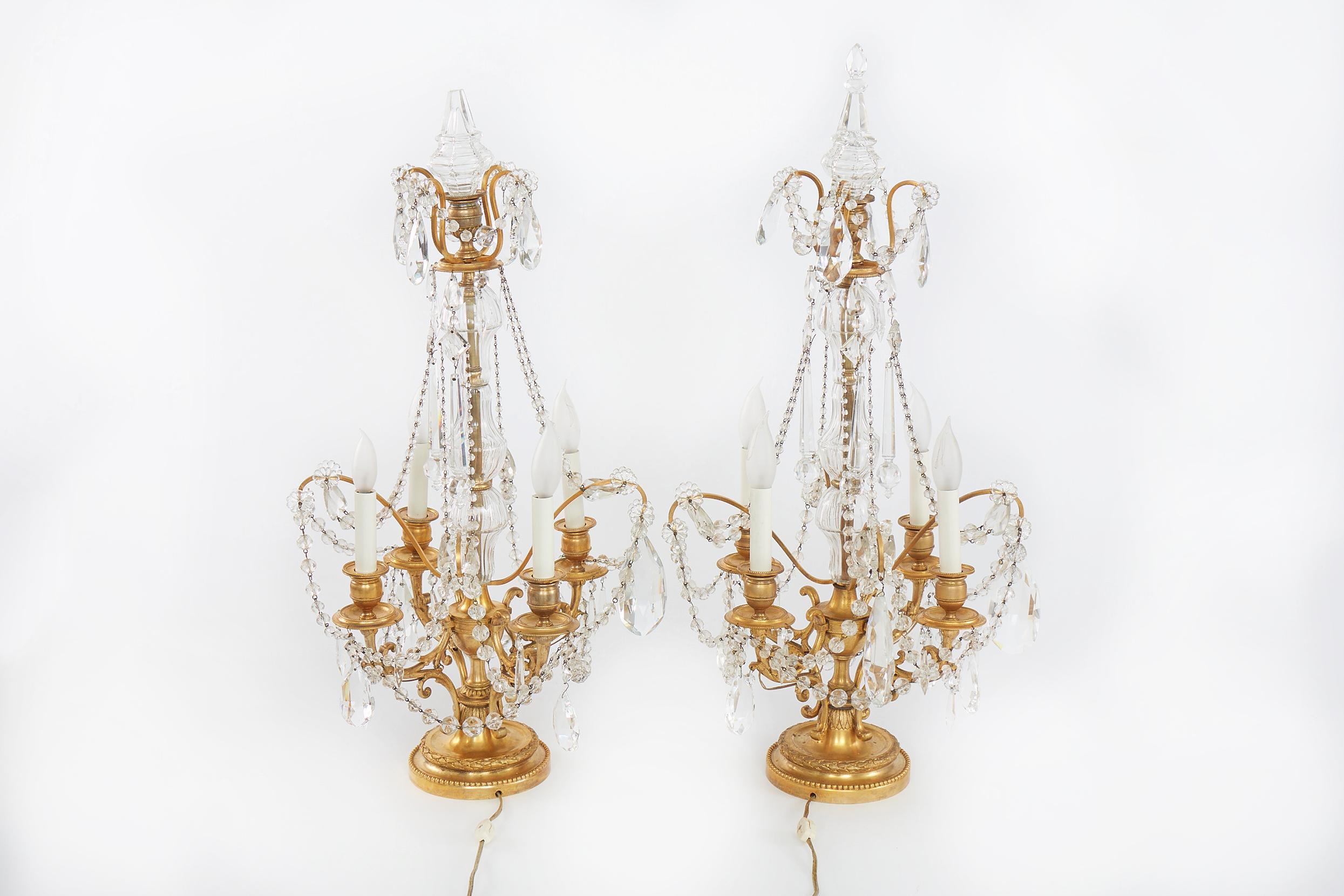 Gilded bronze and cut crystal pair girandole table lamps after E.F.Caldwell ( American 1895 - 1959 ). Each girandoles four light and two tiered 
 with cut glass in tear drop formation in various sizes, each capped with a flower. Slim bulbous neck of