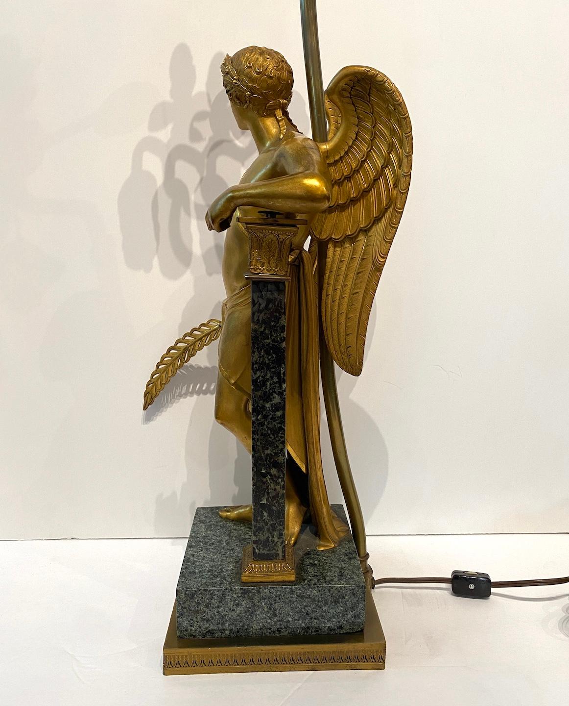 A beautiful, gold bronze dore' figural lamp on marble base. The winged figure carries a plume and a laurel leave crown adorns his head. 3 lights. Wired for USA. Custom square off white linen shade with twisted rope of later date.  Base: 6.5