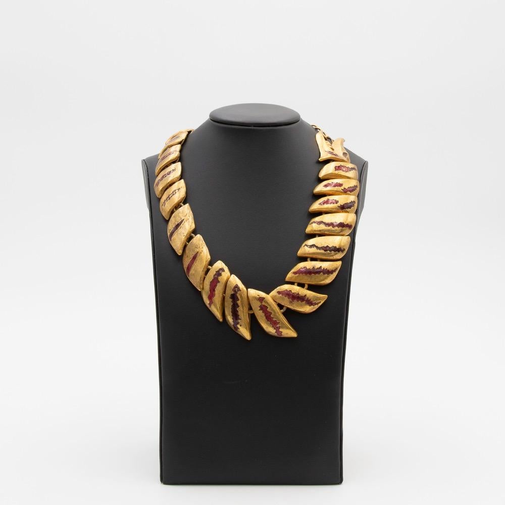 Necklace made of gilded bronze representing a dragon holding in its mouth a chain on which is suspended a stylized woman.
The necklace is constructed so that the dragon's mouth ends up to the right of the wearer and therefore the character hangs