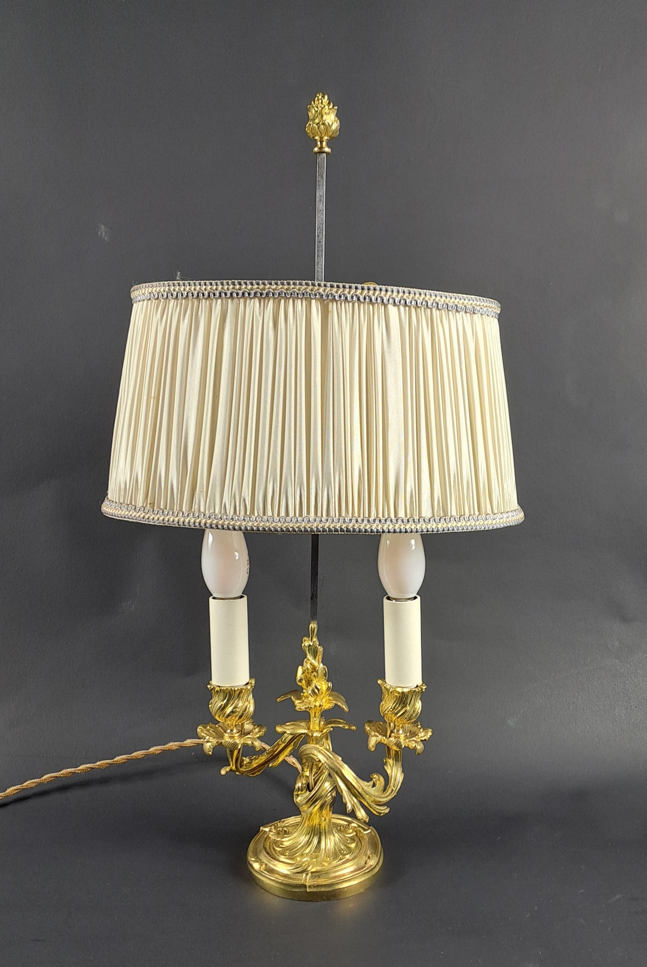 Rococo style lamp in gilded and chiseled bronze with two light arms and featuring a beautiful oblong lampshade in beige silk.

French work from the end of the 19th century and very early 20th century.

Very good condition, electrified by our