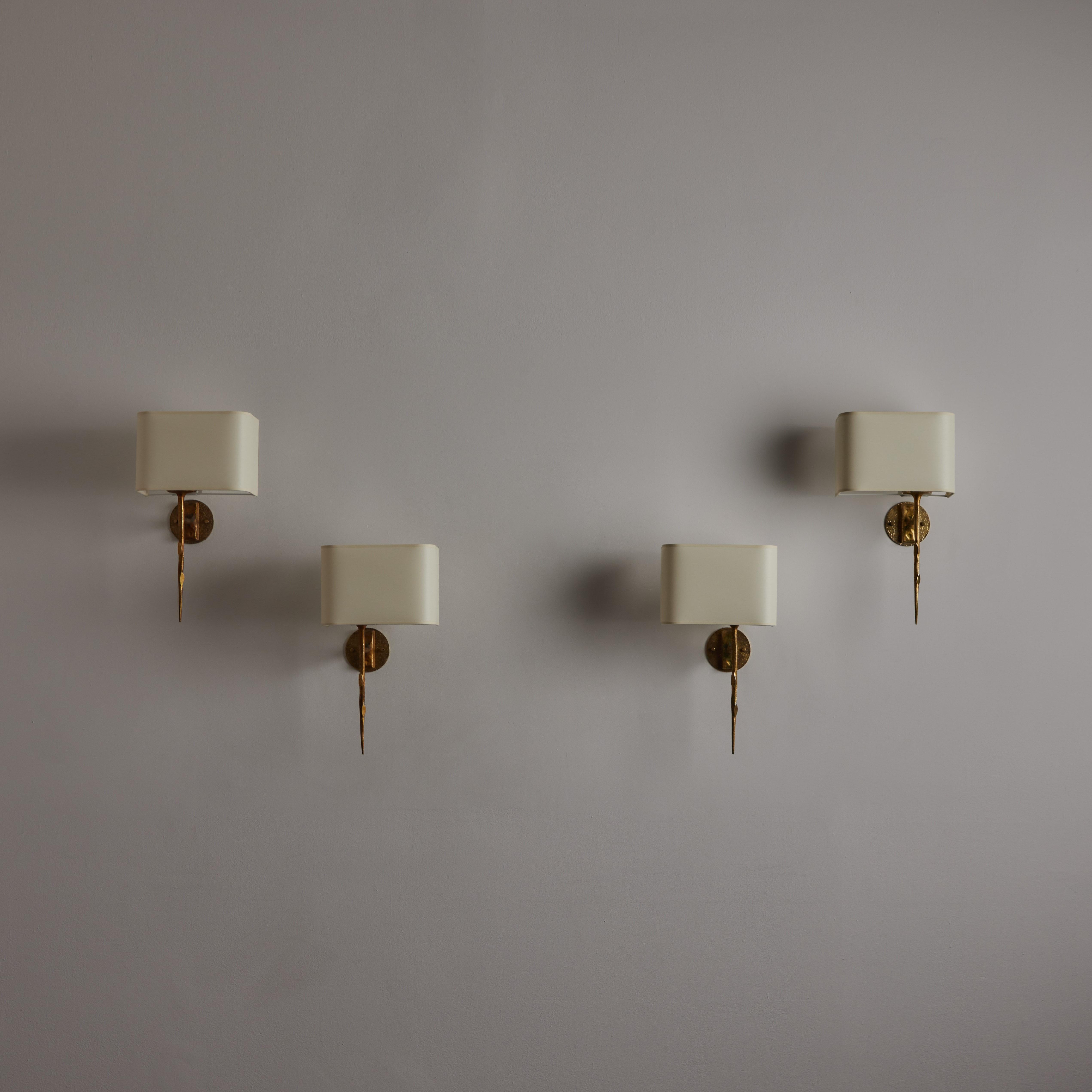Gilded bronze sconces by Maison Arlus. Designed and manufactured in France, Circa the 1960s. Hammered casted brass armatures paired with linen rectangle shades. The shades are mounted on a slider track which allows user to move the shade from left