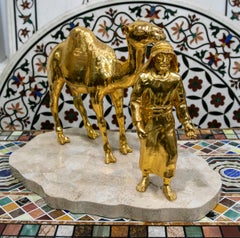 Escultura de bronce dorado con base de mármol de un hombre árabe con un caballo