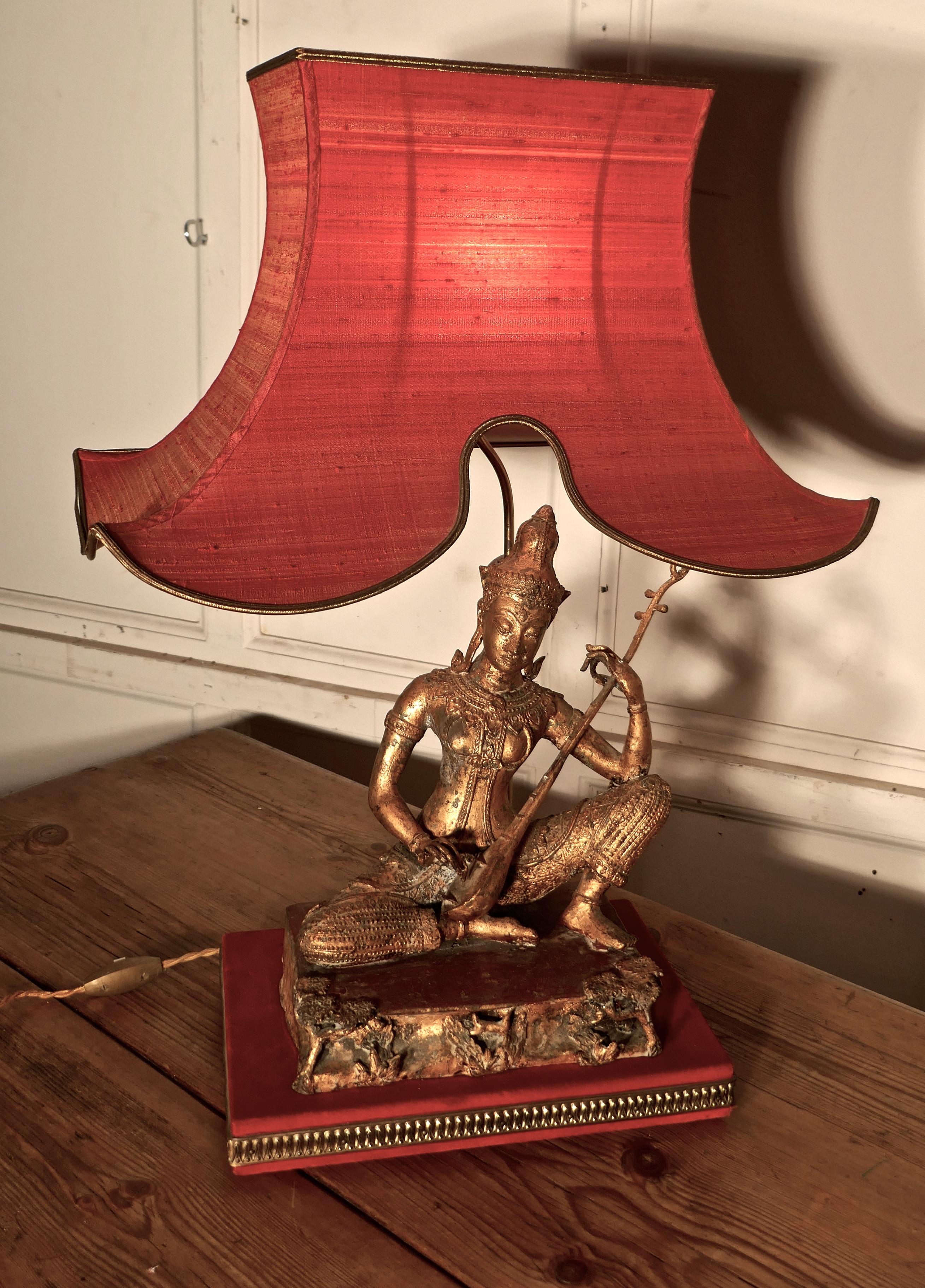Gilded bronze seated Buddha table lamp


This is an excellent piece with an oriental theme

The Female bronze statue is seated playing a sitar, it has an old worn gold finish and this is set on a metal platform which is decorated in fine detail