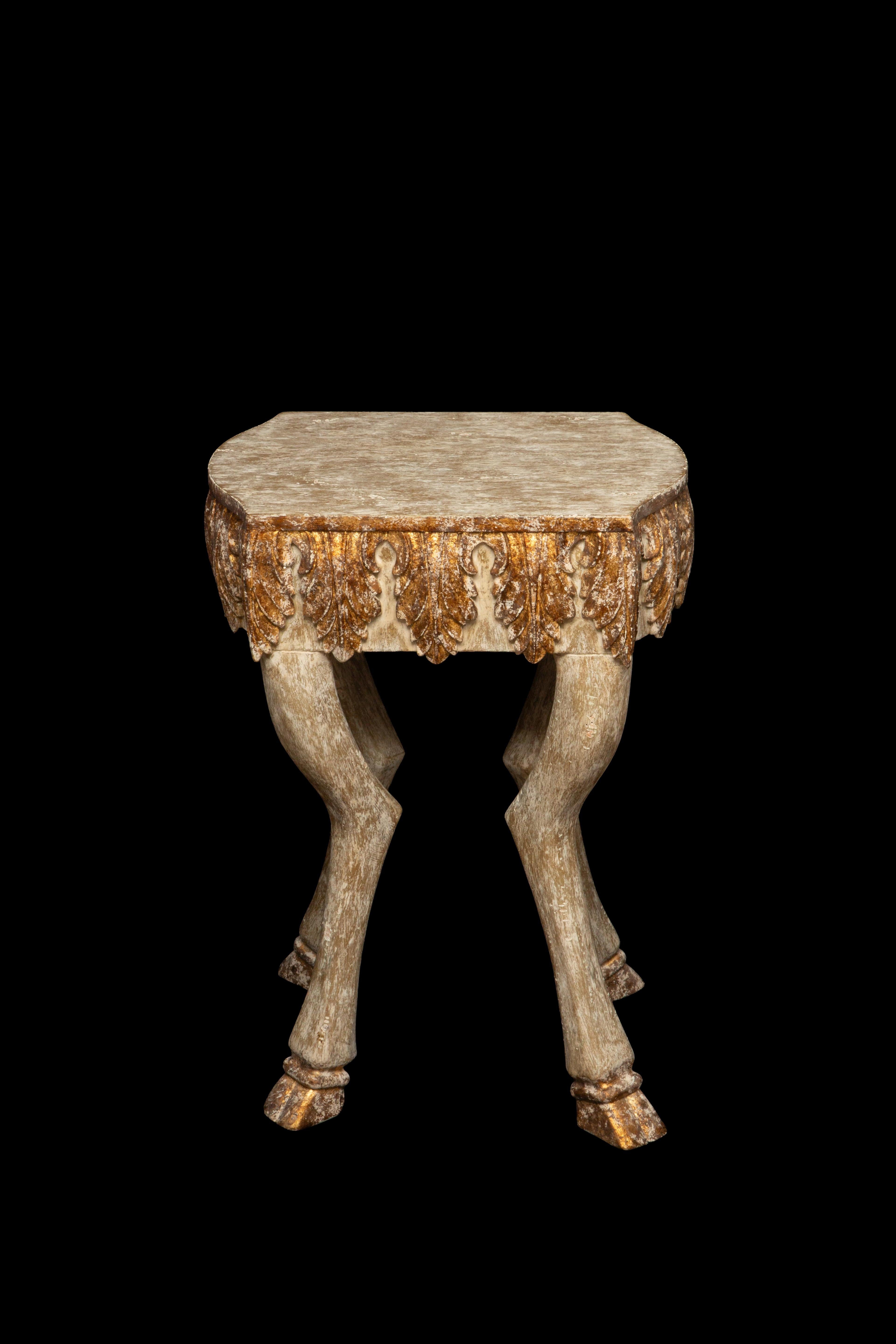 Exquisite Carved Wood Side Table featuring a stunning white-washed finish adorned with delicate gilded accents, all supported by intricately carved hoof legs. Crafted with meticulous attention to detail, this charming side table from the renowned