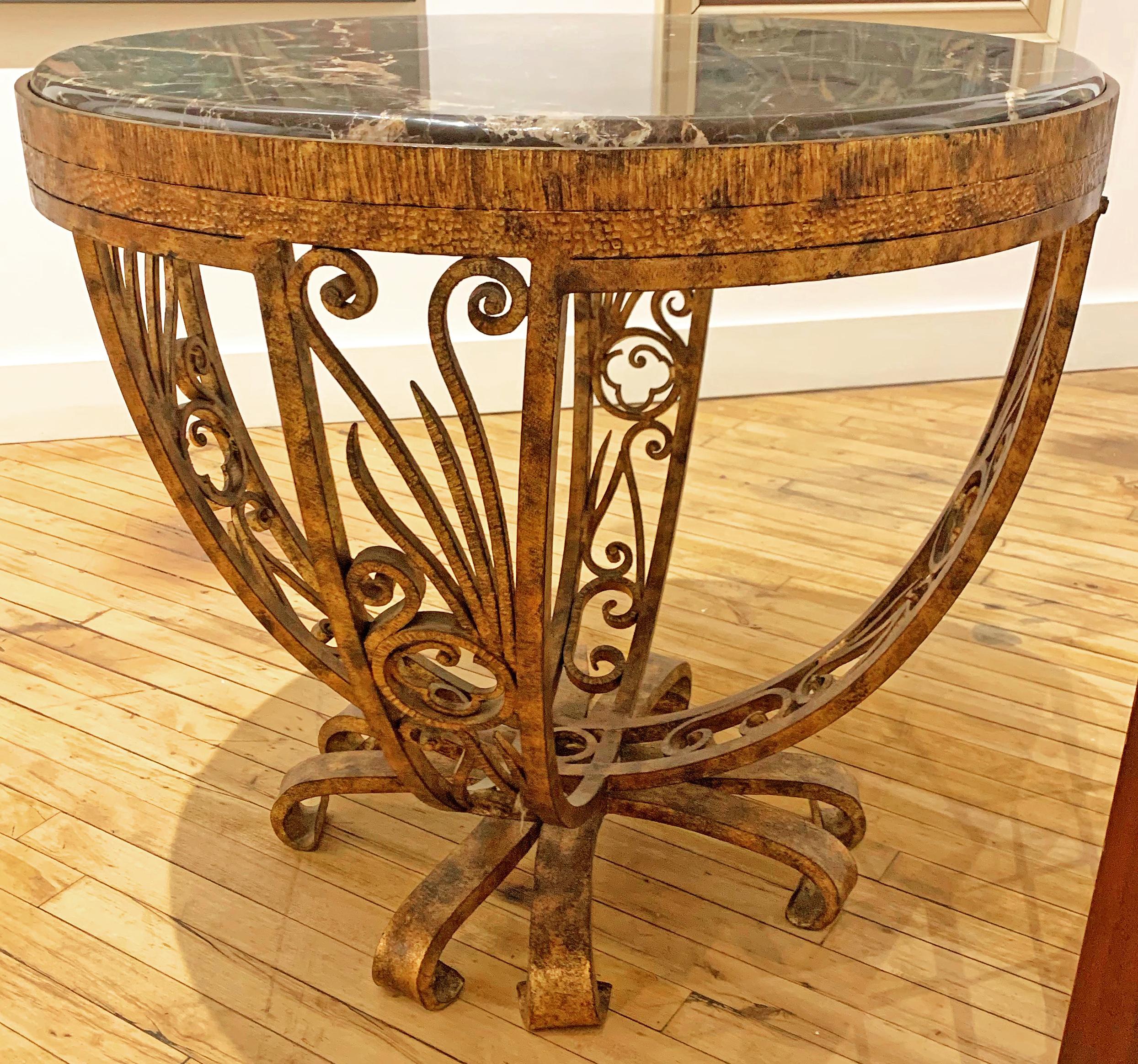 Superbly crafted of wrought iron gilded in an old gold finish with an inset black-veined marble top, this Art Deco revival table is heavy, substantial and impressive. Shaped like a timpani drum with a round, flat top and curving sides, it is