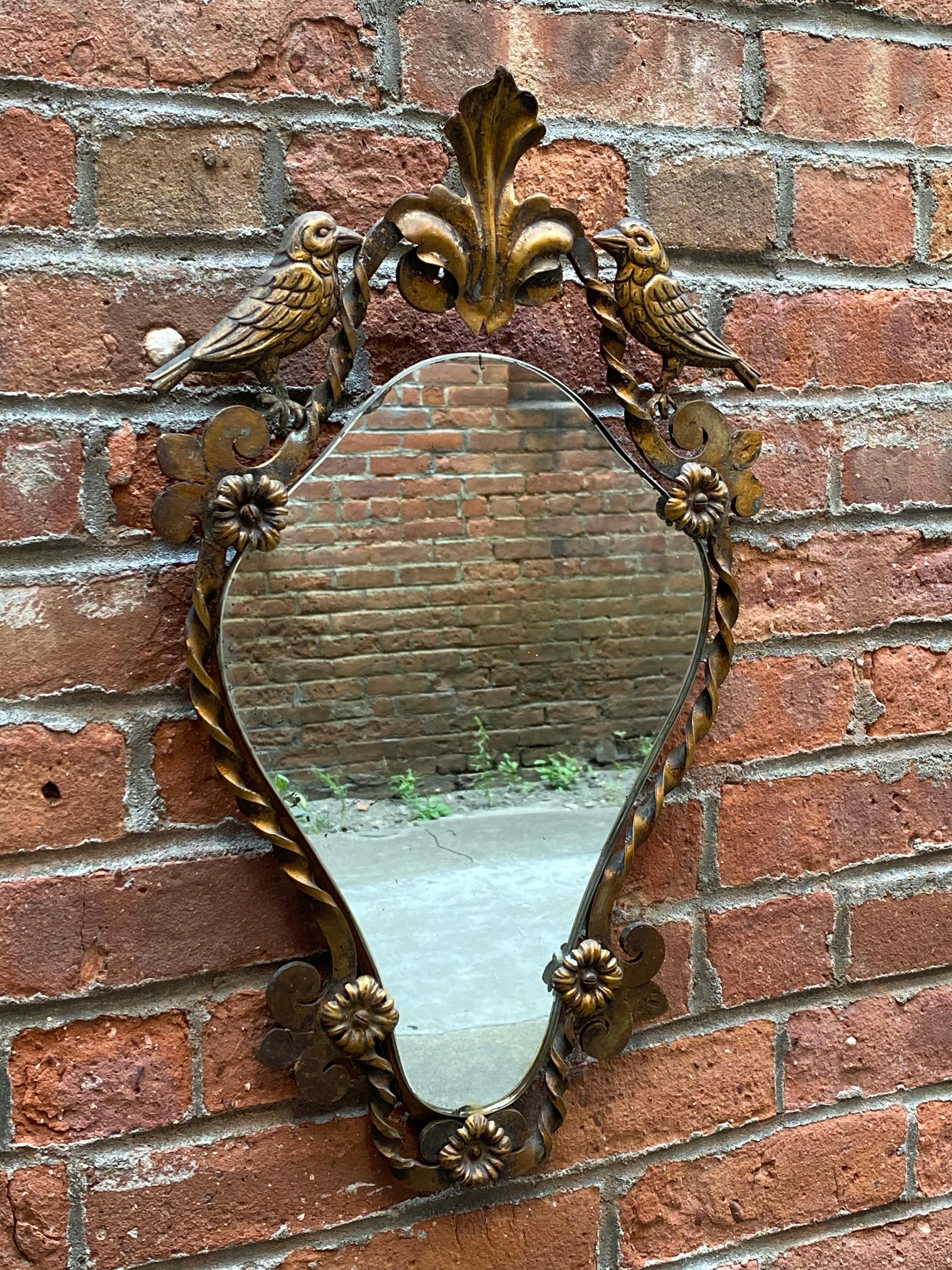 Rosettes, birds, fleur d'lis and twisted iron. Elegant and beautiful. Antiqued gold finish, circa 1920-1930. Overall good condition with some silvering losses to the mirror and edges (see photos).

Measures: Approximately .50