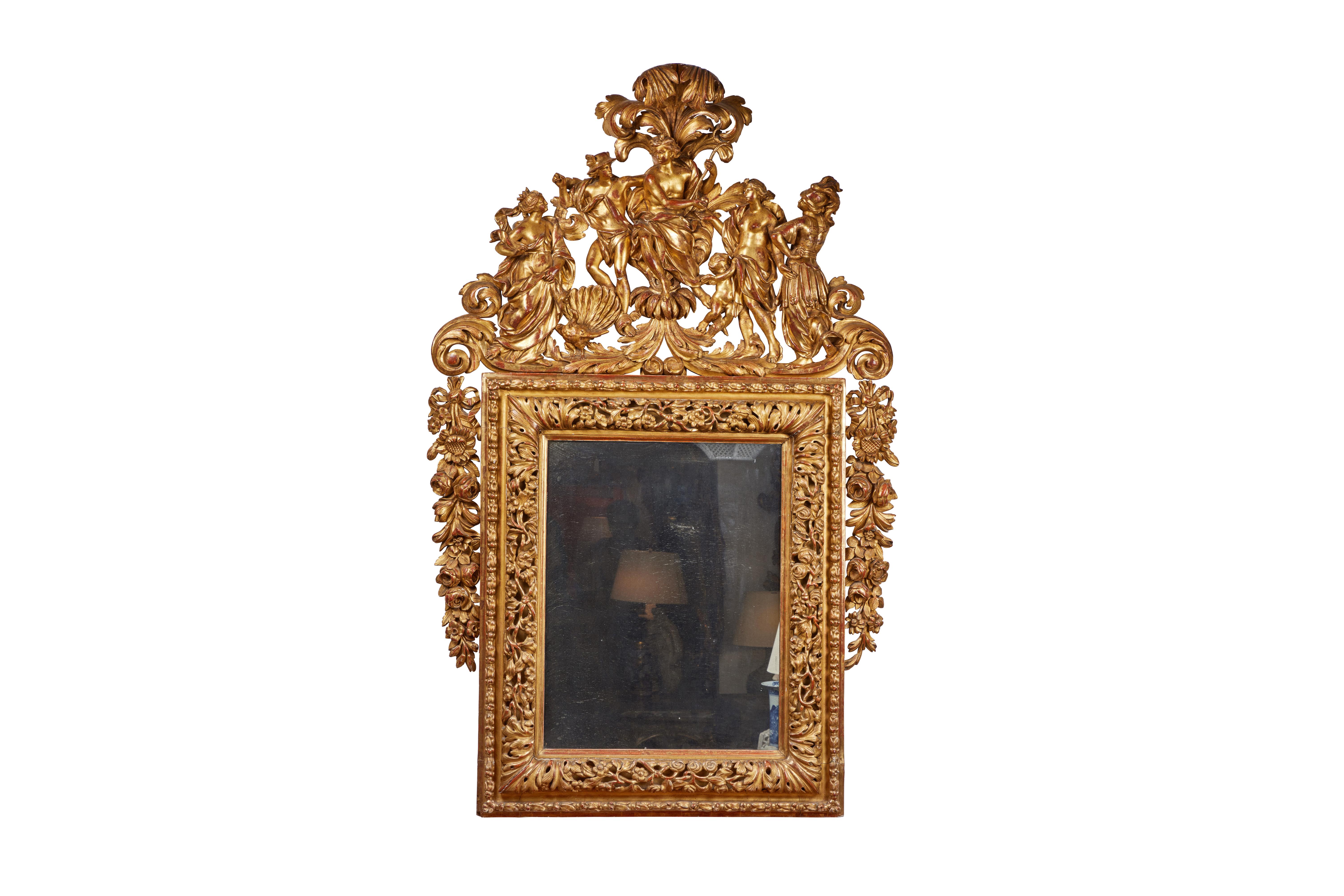 An elaborately hand carved and gilded Louis XIV style frame with original slightly mottled mercury mirror.