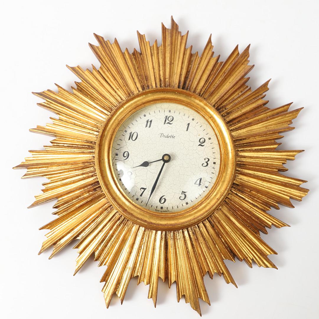 Wood frame with brass clock face with a craquelure and black clock hands and index. Fitted with a battery movement. Made in France by Vedette in the 1950s.