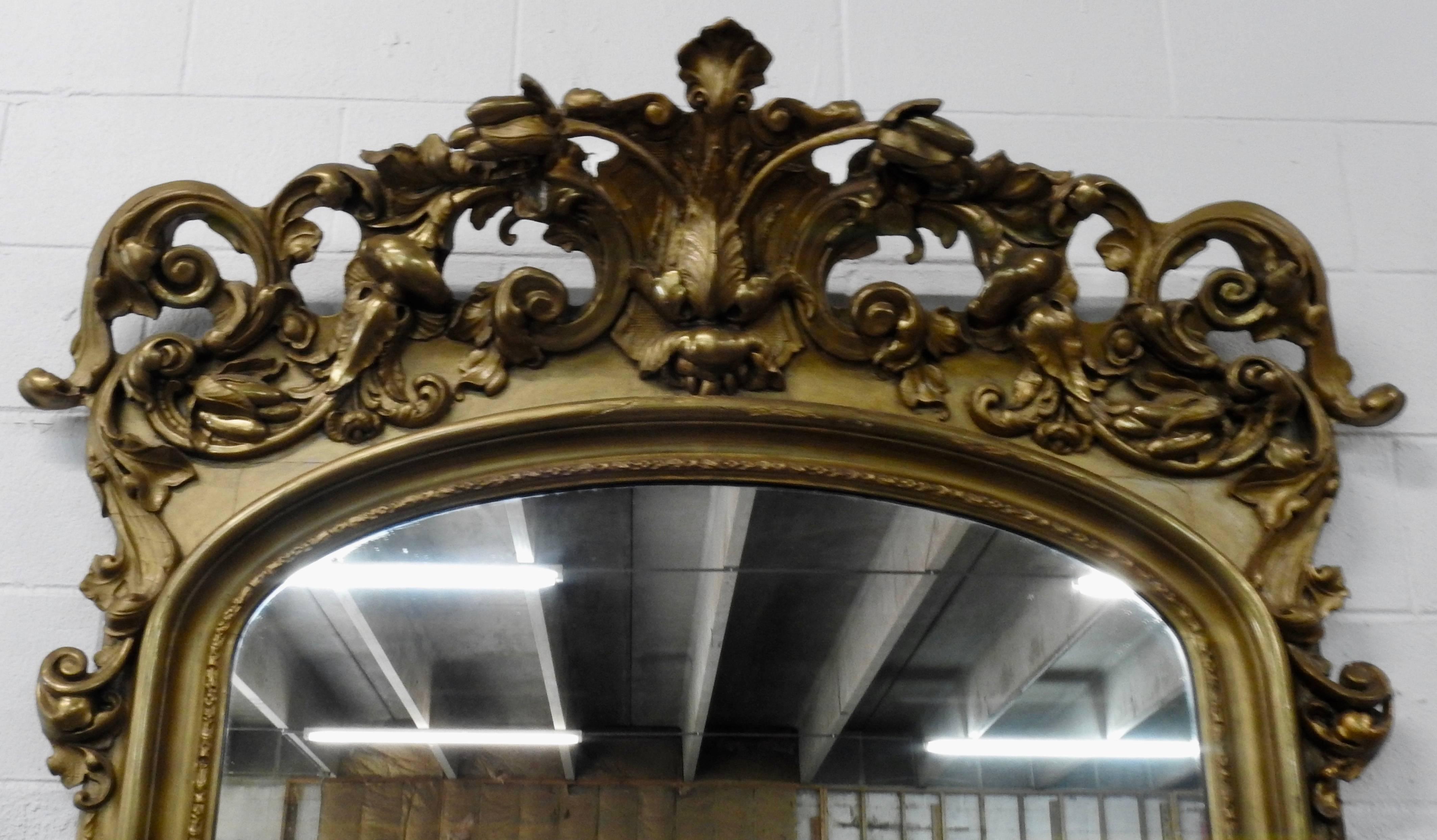 This is an elegant Victorian mirror that sits atop a beveled marble top pedestal with four cabriole legs. Beautiful scrollwork with a leaf motif add to the beauty of this piece. The pedestal has lots of openwork starting in the center with a shell
