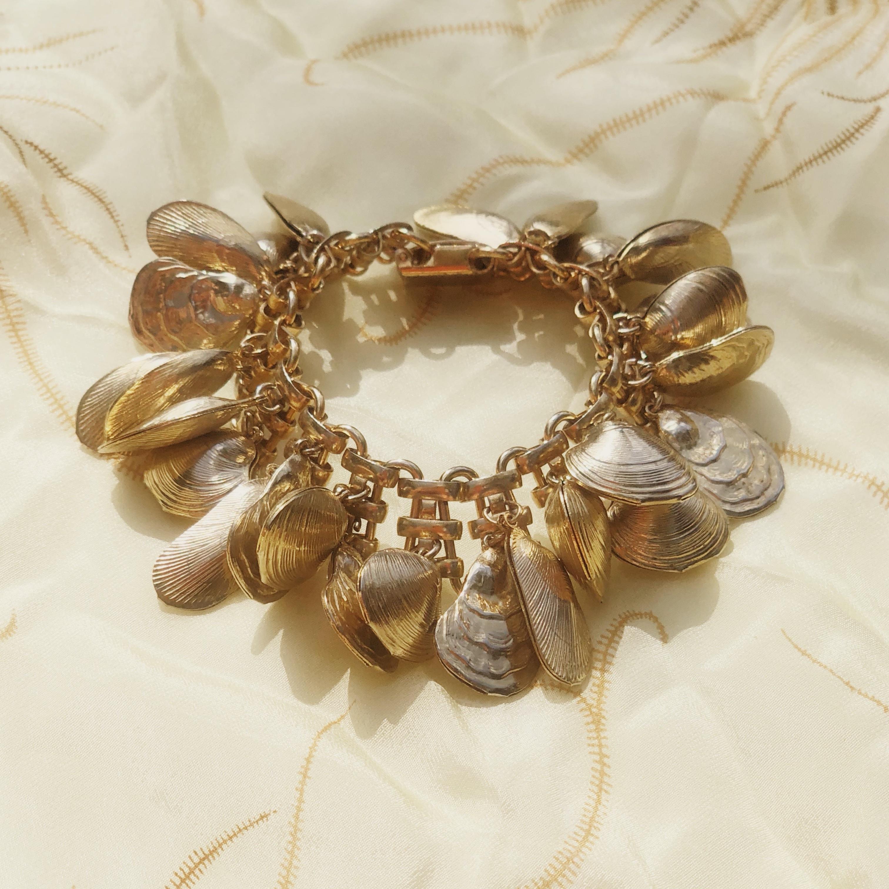 This rare and iconic Napier shell charm bracelet, designed by Eugene Bertolli, is a favorite among vintage jewelry collectors.  A cluster of three dimensional gold plated seashells jingle and jangle with every move you make - a wonderful piece for