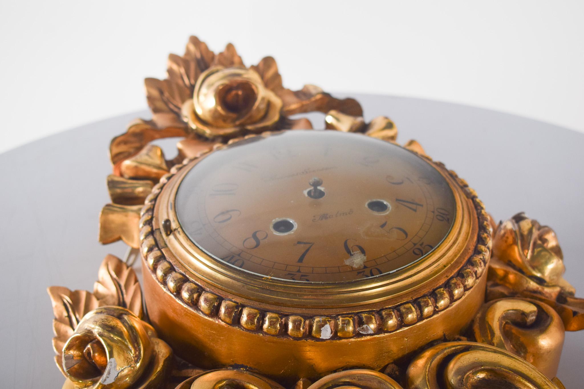 Gilded wood wall clock with Andreas Svensson dial, Malmo. Impressive handiwork from the early 20th century, with a classic and sophisticated design. The richly decorated structure is made of gilded wood with carvings that recall the Baroque style.