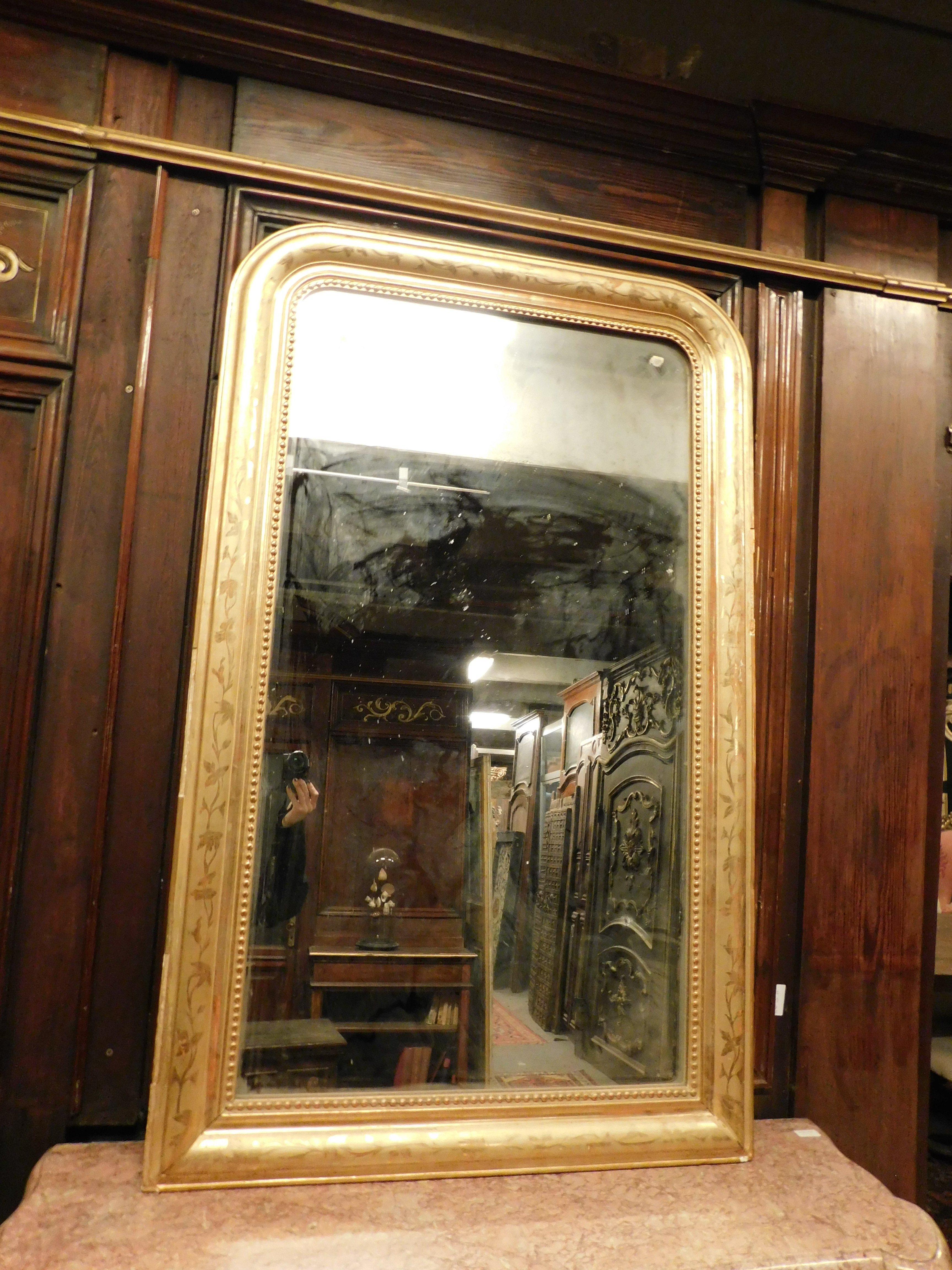 Antique solid wood mirror, decorated and gilded with rounded corners. It has a frame with successive leaf motifs and carved beads. The upper part has rounded corners to give even more elegance to the mirror. Original from the 19th century,