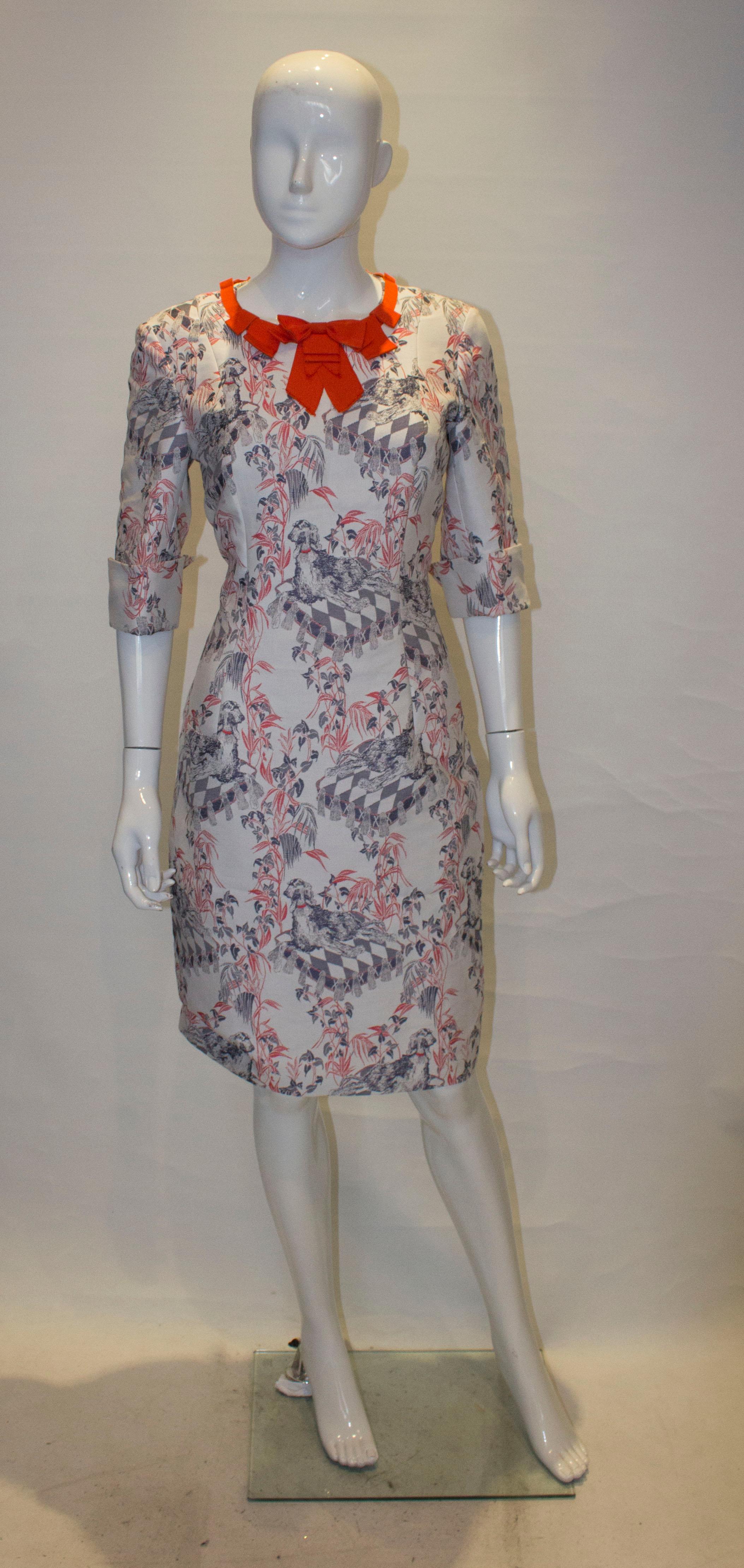A fun dress by Giles. In a wonderful dog print with a ribbon neckline, the dress has short sleaves with cuff turn backs and is fully lined. Marked size 42