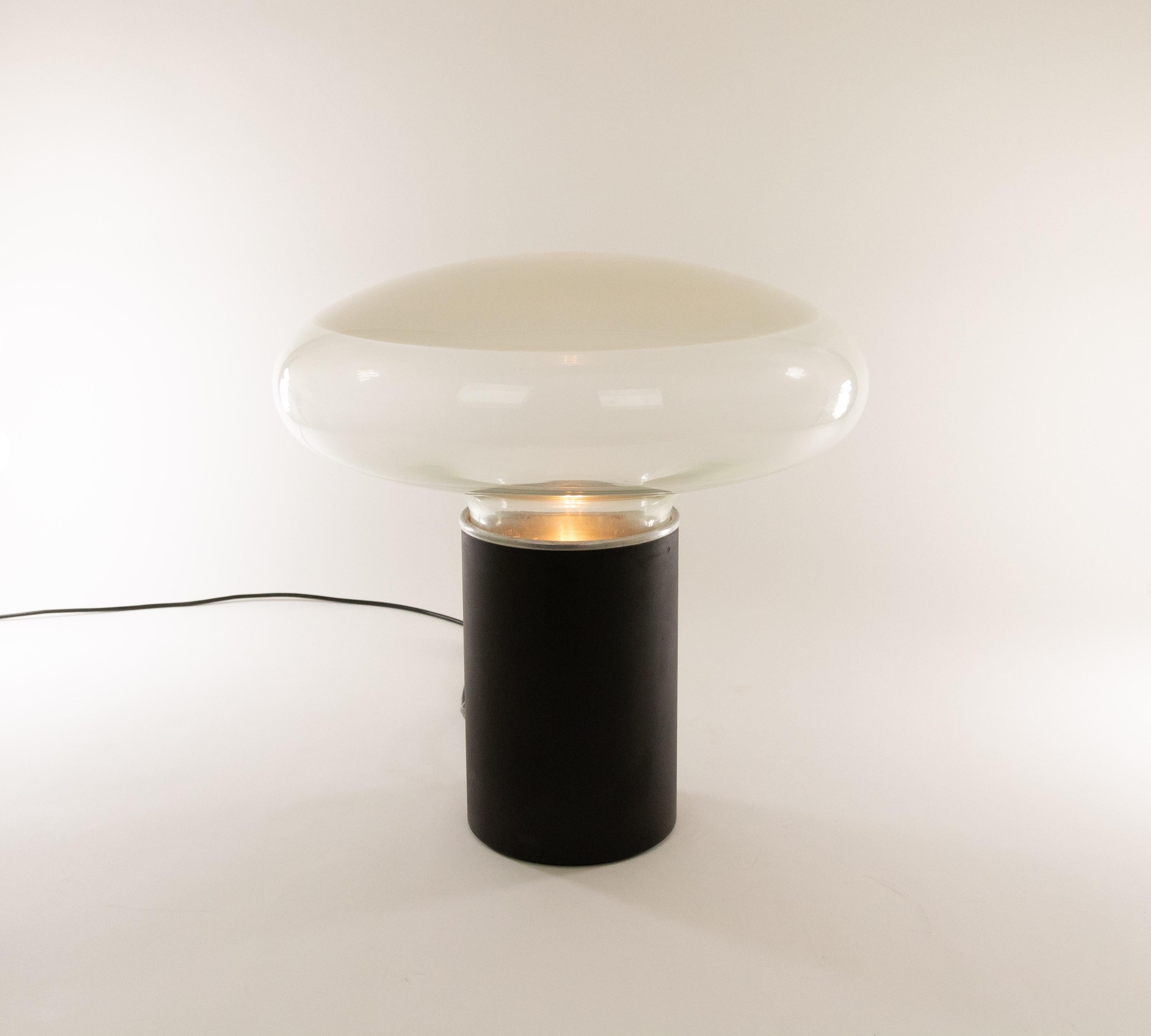 Gill table lamp designed by Roberto Pamio for Leucos in the 1960s.

The lamp consists of two main parts; the metal cylinder shaped base and a diffuser in glass that is partly transparant and partly white. The diffuser sits on an internal metal
