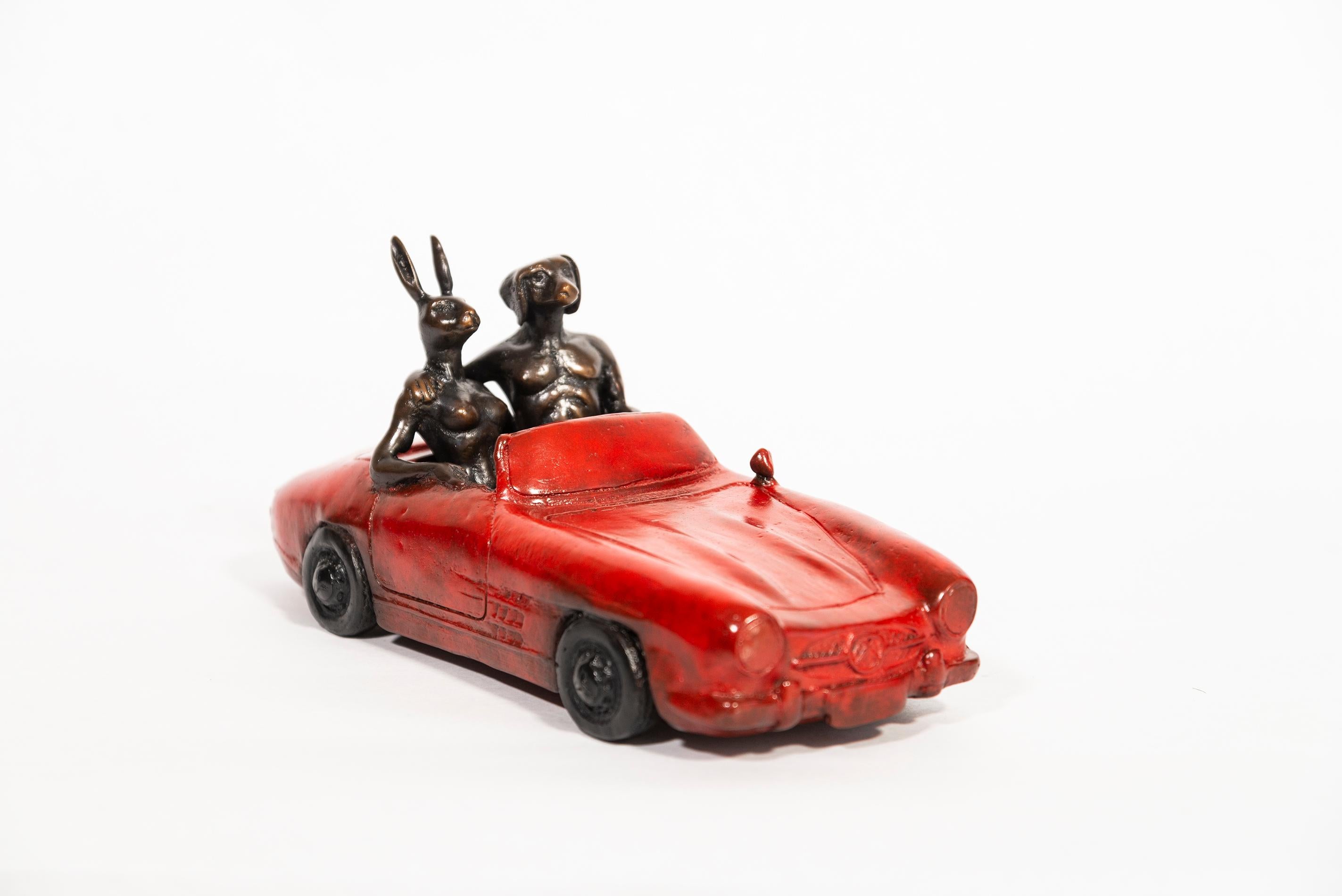 Gillie and Marc have become renowned for their charming tabletop sculptures of a hybrid couple—a rabbitwoman and a dogman who’ve ridden scooters, dined and in this piece can be seen cruising in a hot red convertible. For the dynamic artistic couple,