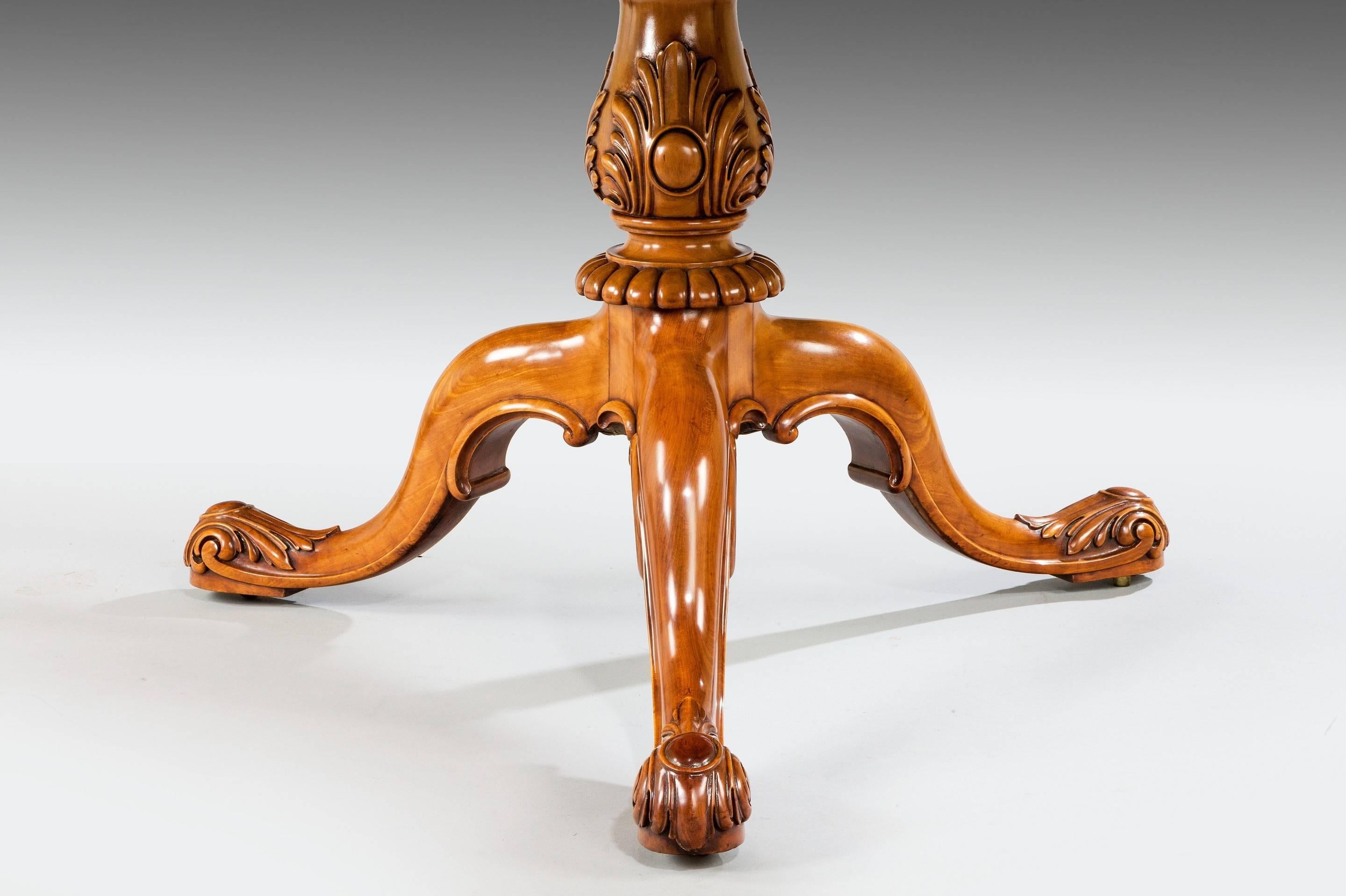 A superb oval shaped satinwood and kingwood centre table, with cotton-reel carved edge, on a leaf-carved baluster stem and cabriole legs carved with foliage and cabochons.
